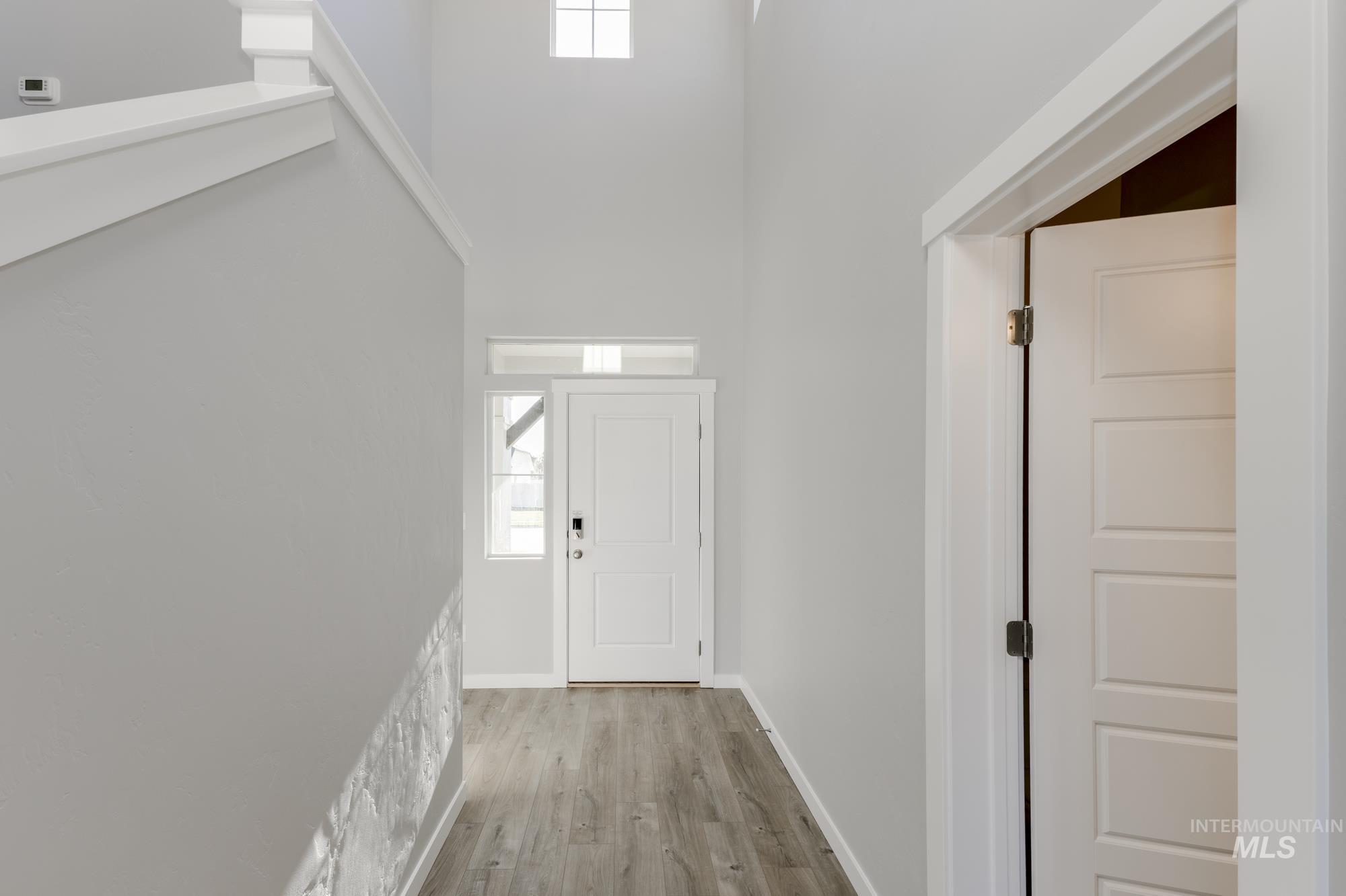 Foyer featuring light wood-style flooring and a towering ceiling