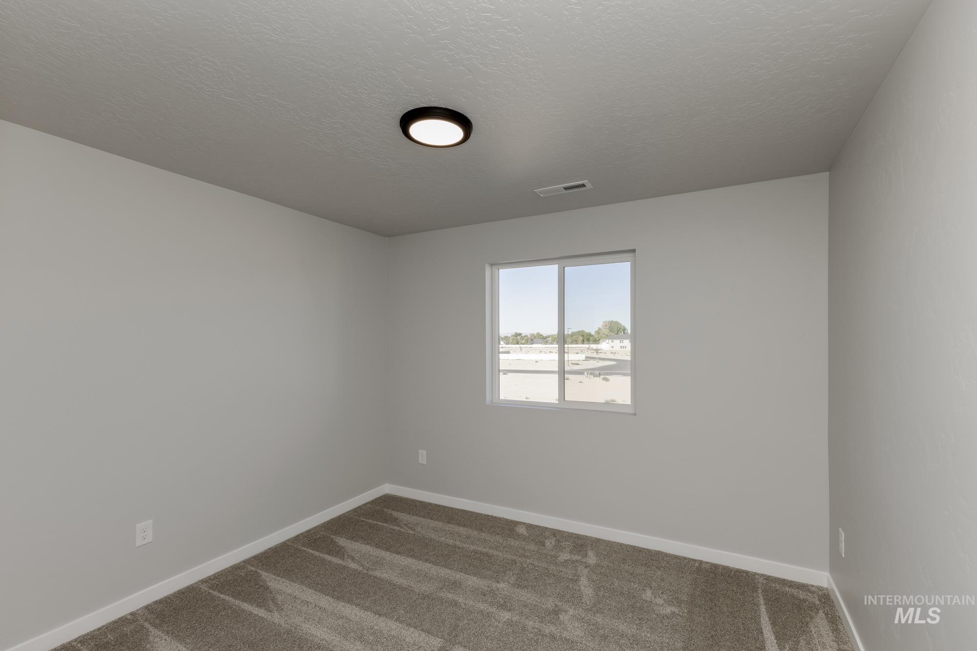 Empty room featuring dark carpet and a textured ceiling
