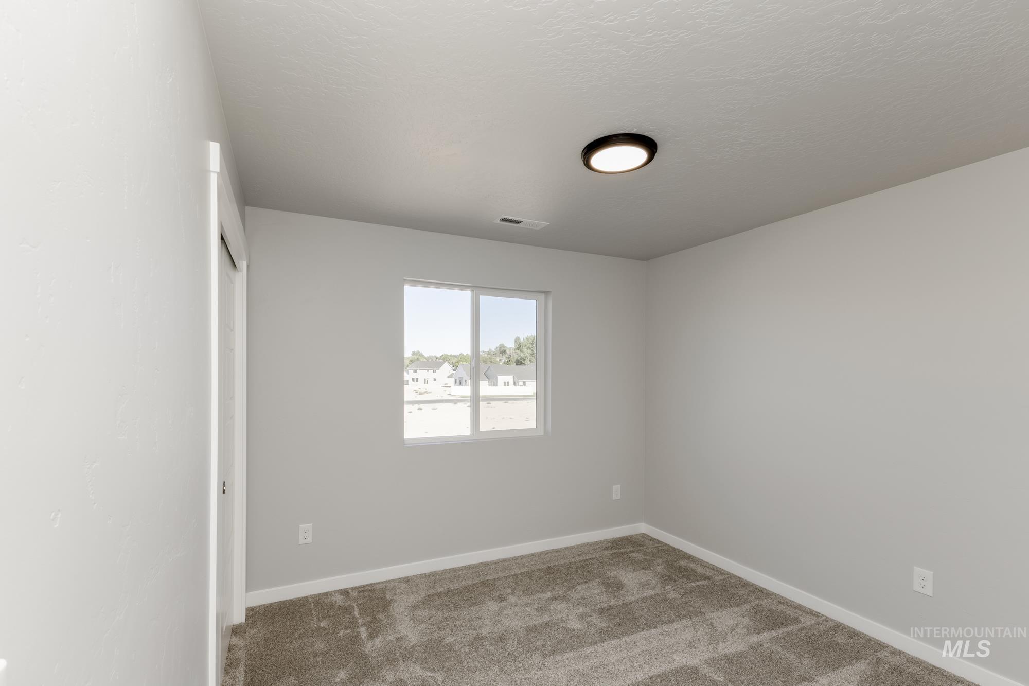 Carpeted spare room with baseboards and a textured ceiling