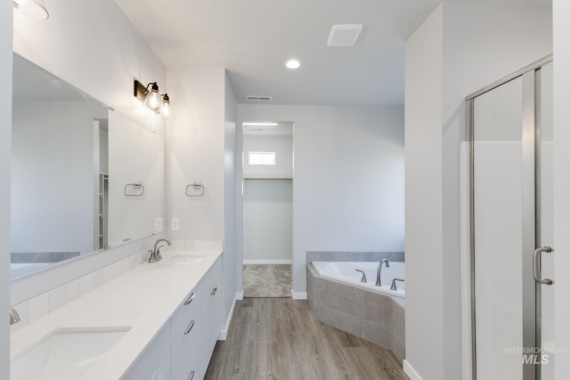 Full bath featuring light wood-type flooring, double vanity, a garden tub, recessed lighting, and a shower stall