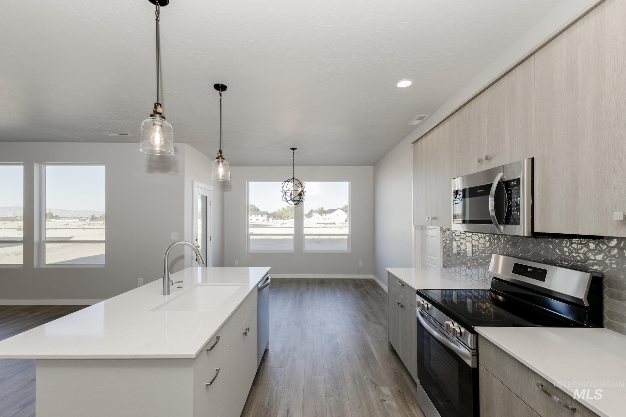Kitchen with stainless steel appliances, pendant lighting, modern cabinets, dark wood-type flooring, and light stone counters