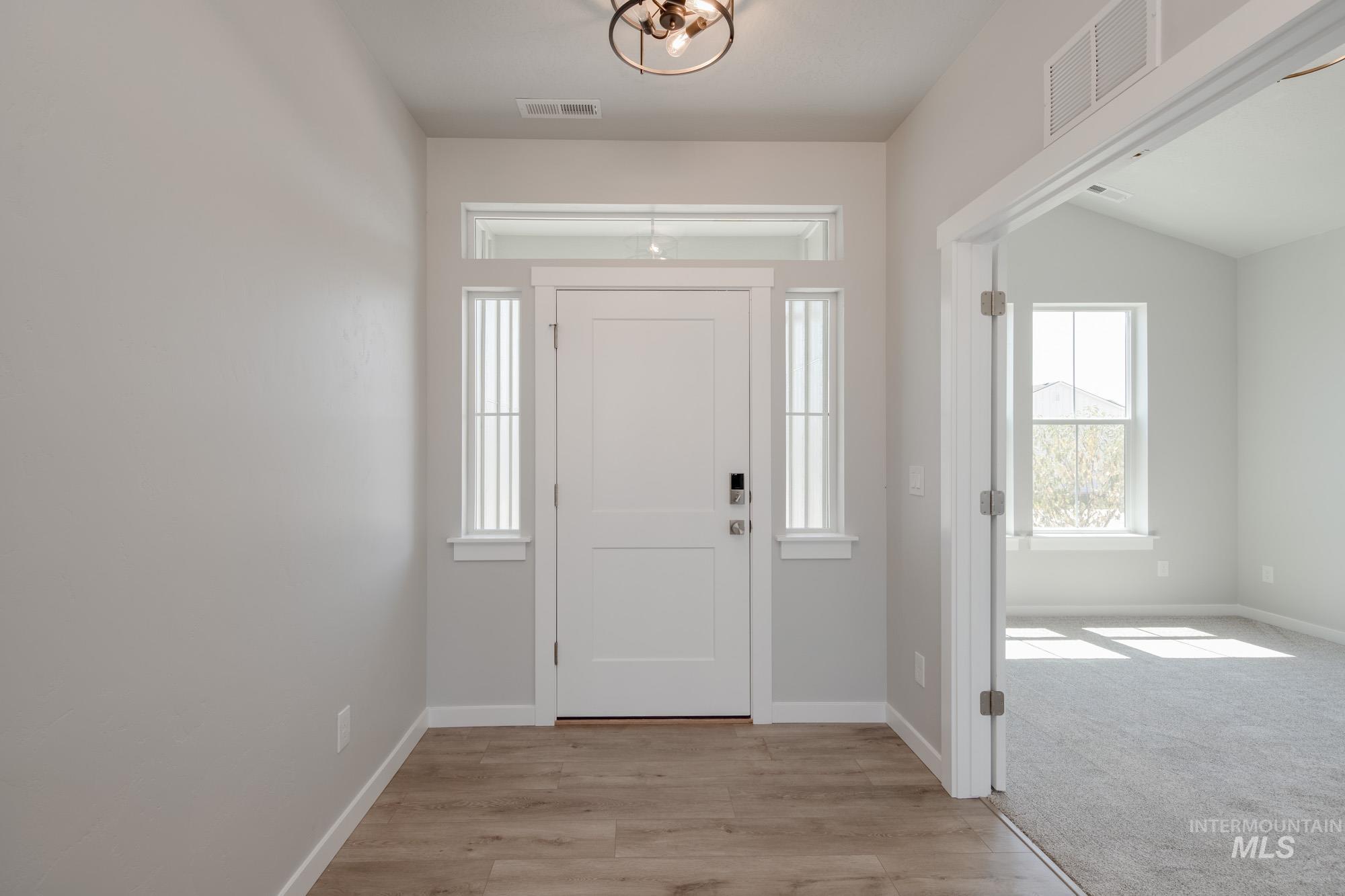 Foyer featuring light wood-style flooring and light carpet