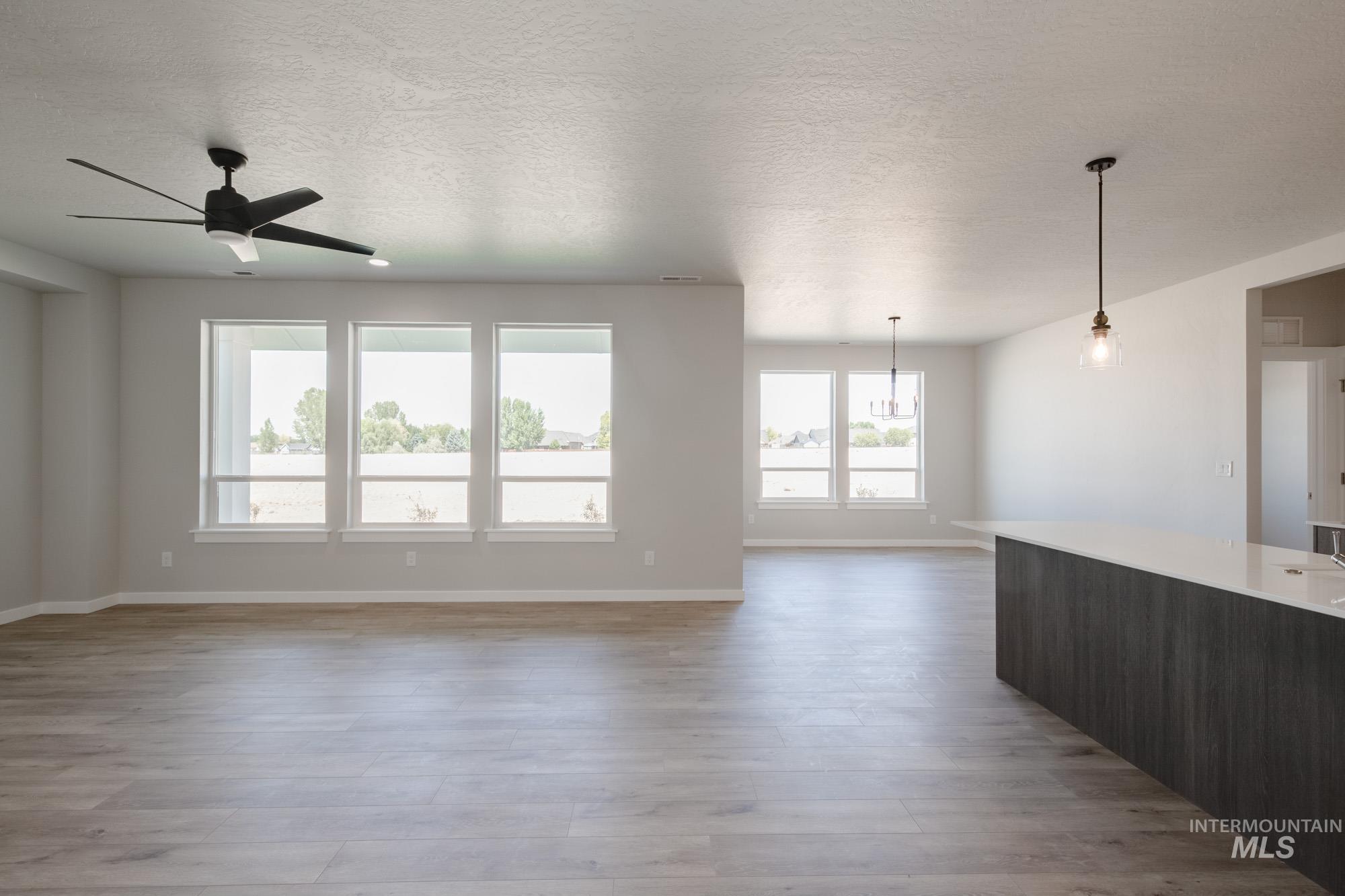 Unfurnished living room featuring a textured ceiling, light wood-style flooring, and a ceiling fan