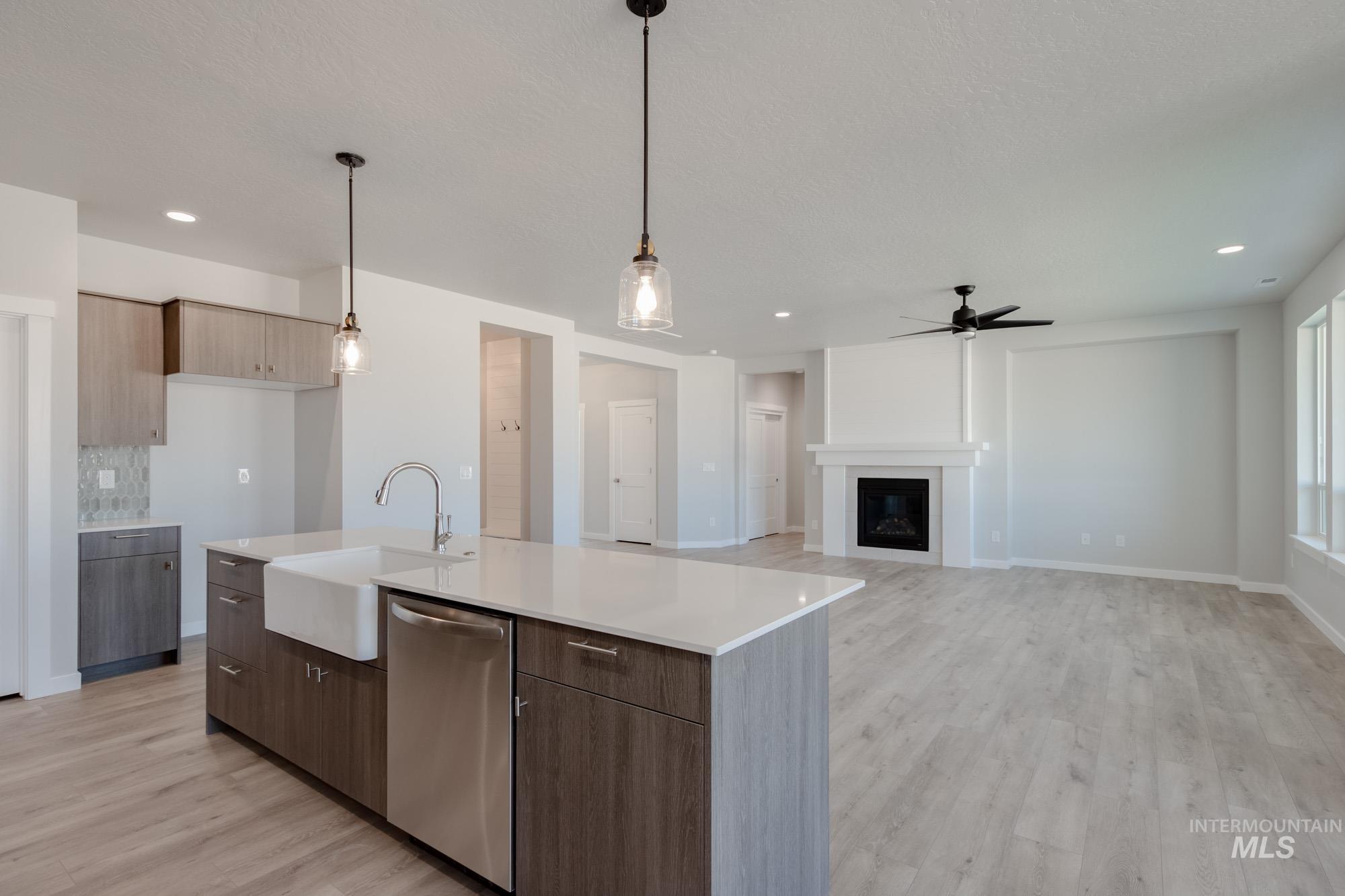 Kitchen featuring stainless steel dishwasher, light wood finished floors, open floor plan, modern cabinets, and recessed lighting
