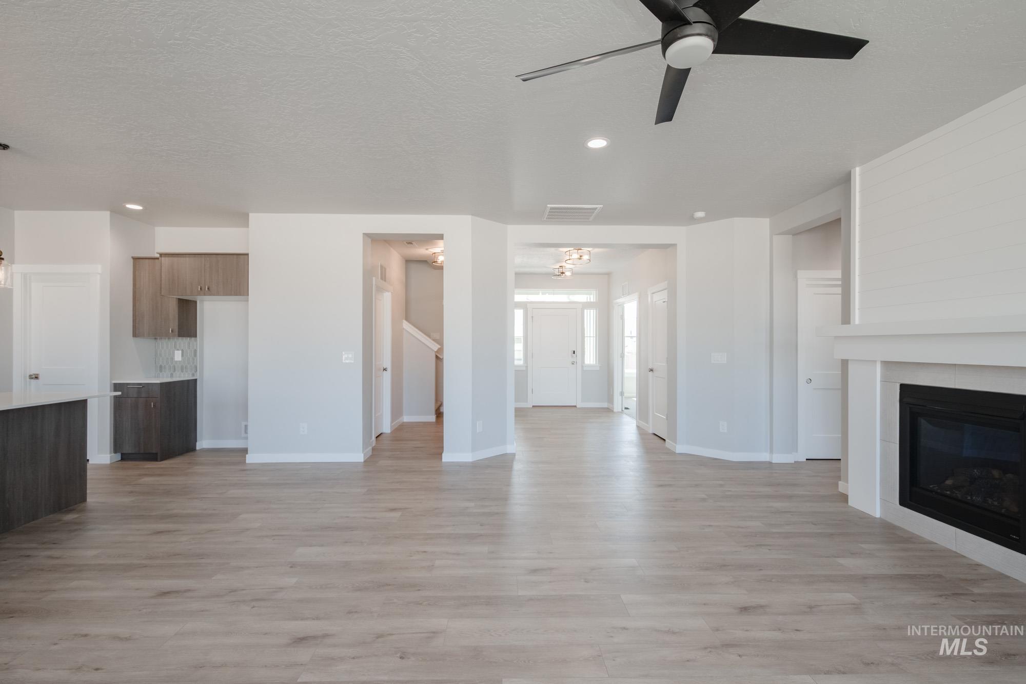 Unfurnished living room featuring light wood finished floors, a tile fireplace, recessed lighting, ceiling fan, and a textured ceiling