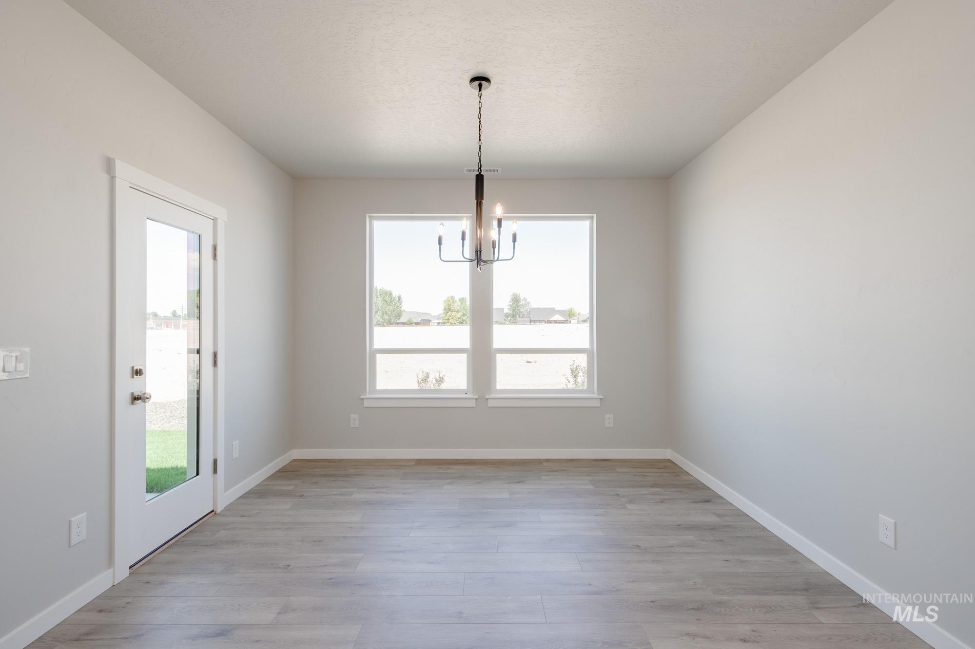 Unfurnished dining area with a chandelier and light wood finished floors