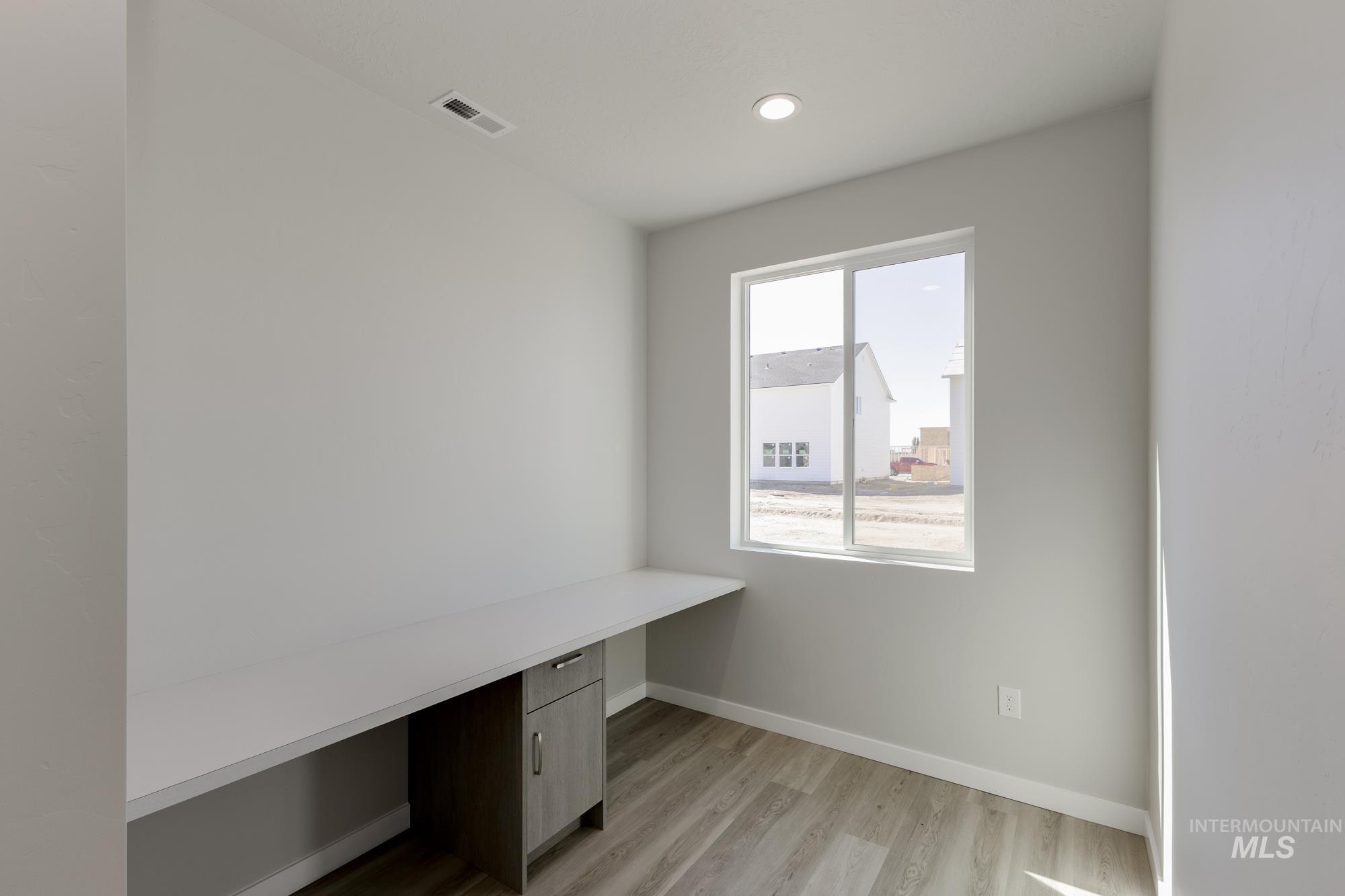 Unfurnished office with built in desk, light wood-style floors, and recessed lighting