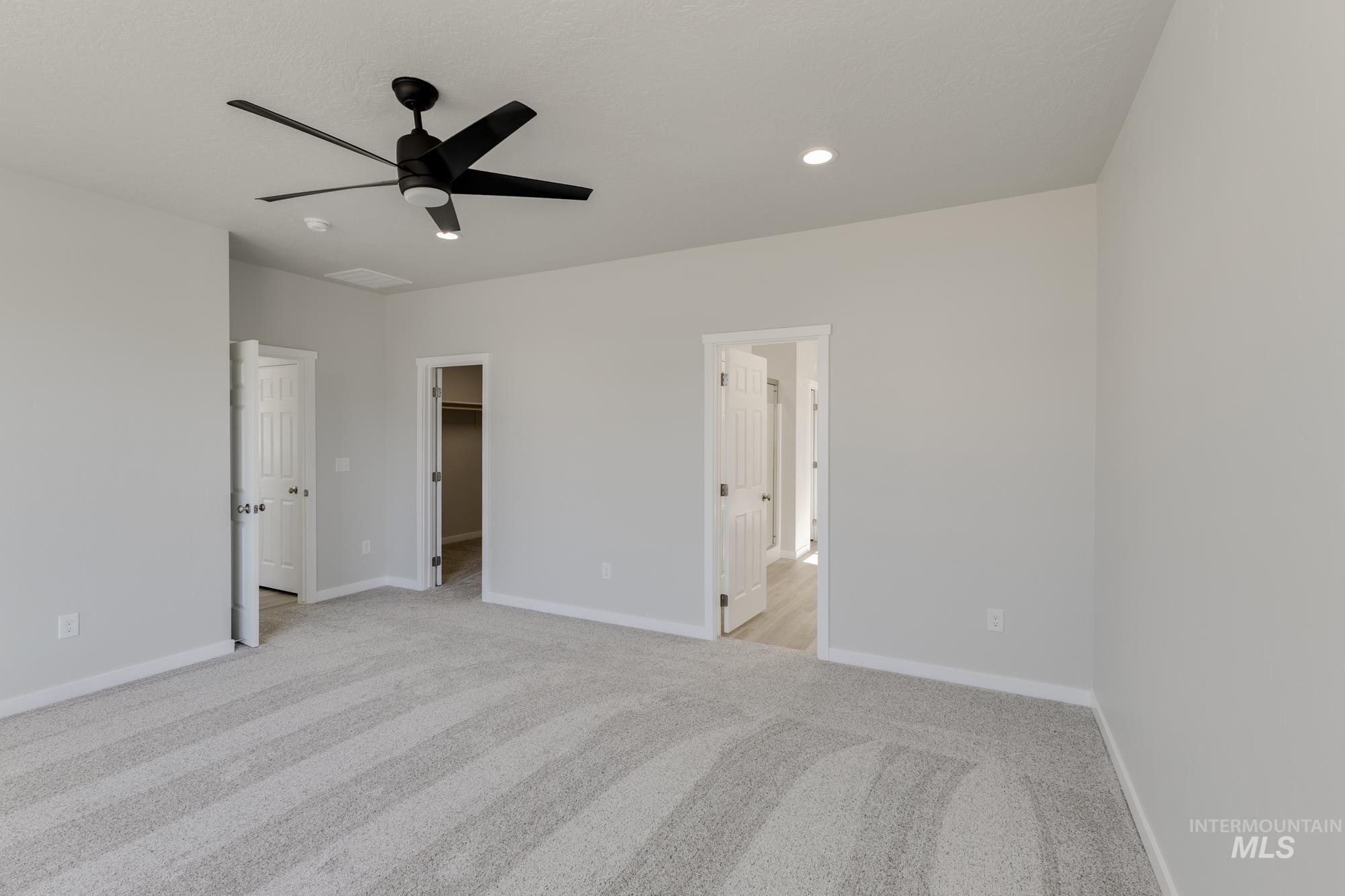 Unfurnished bedroom with a spacious closet, light colored carpet, a ceiling fan, recessed lighting, and ensuite bathroom