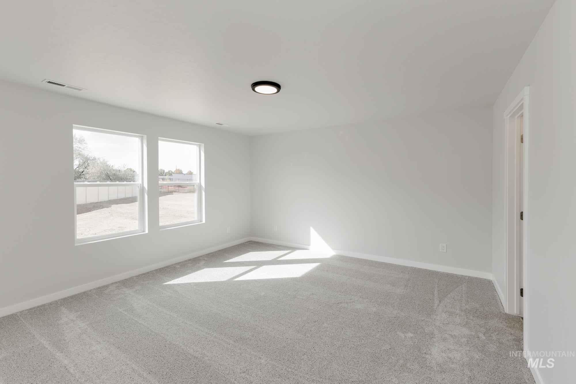 Empty room featuring light colored carpet and baseboards