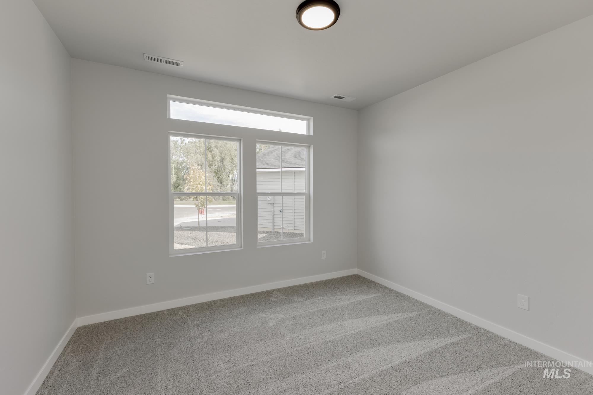 Empty room featuring light colored carpet and baseboards