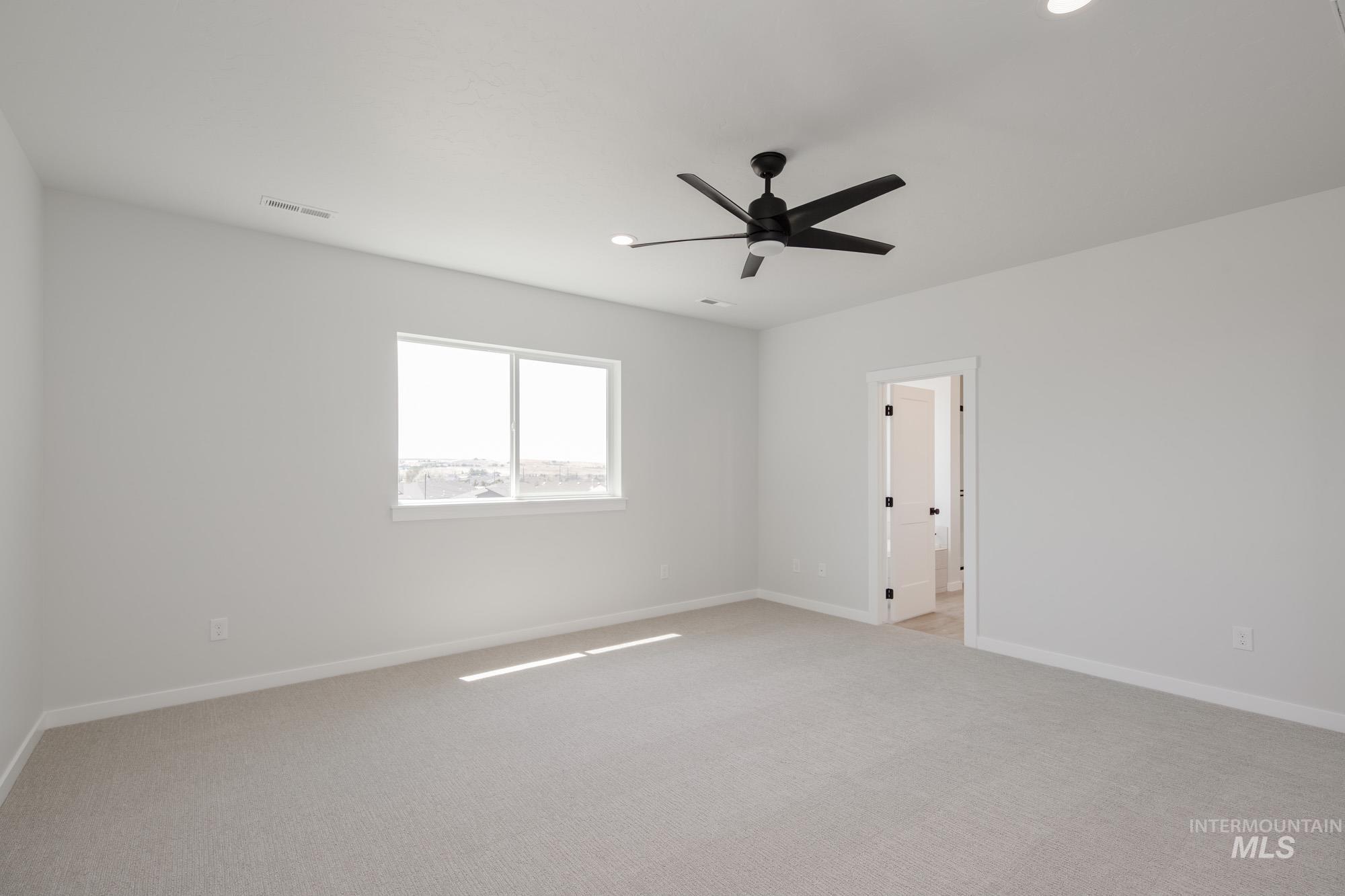 Empty room featuring light colored carpet and ceiling fan