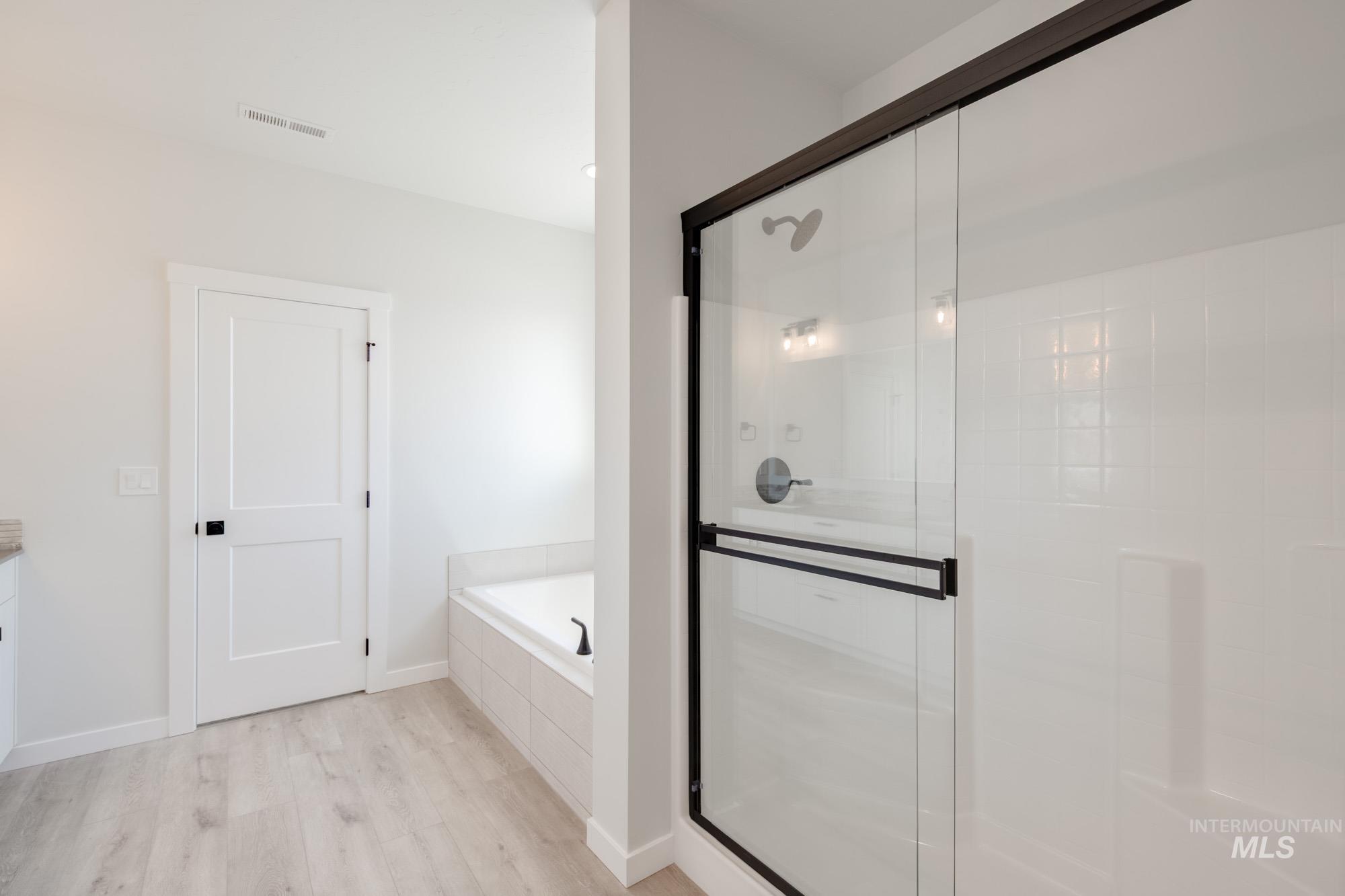 Full bathroom with a bath, light wood finished floors, a stall shower, and vanity