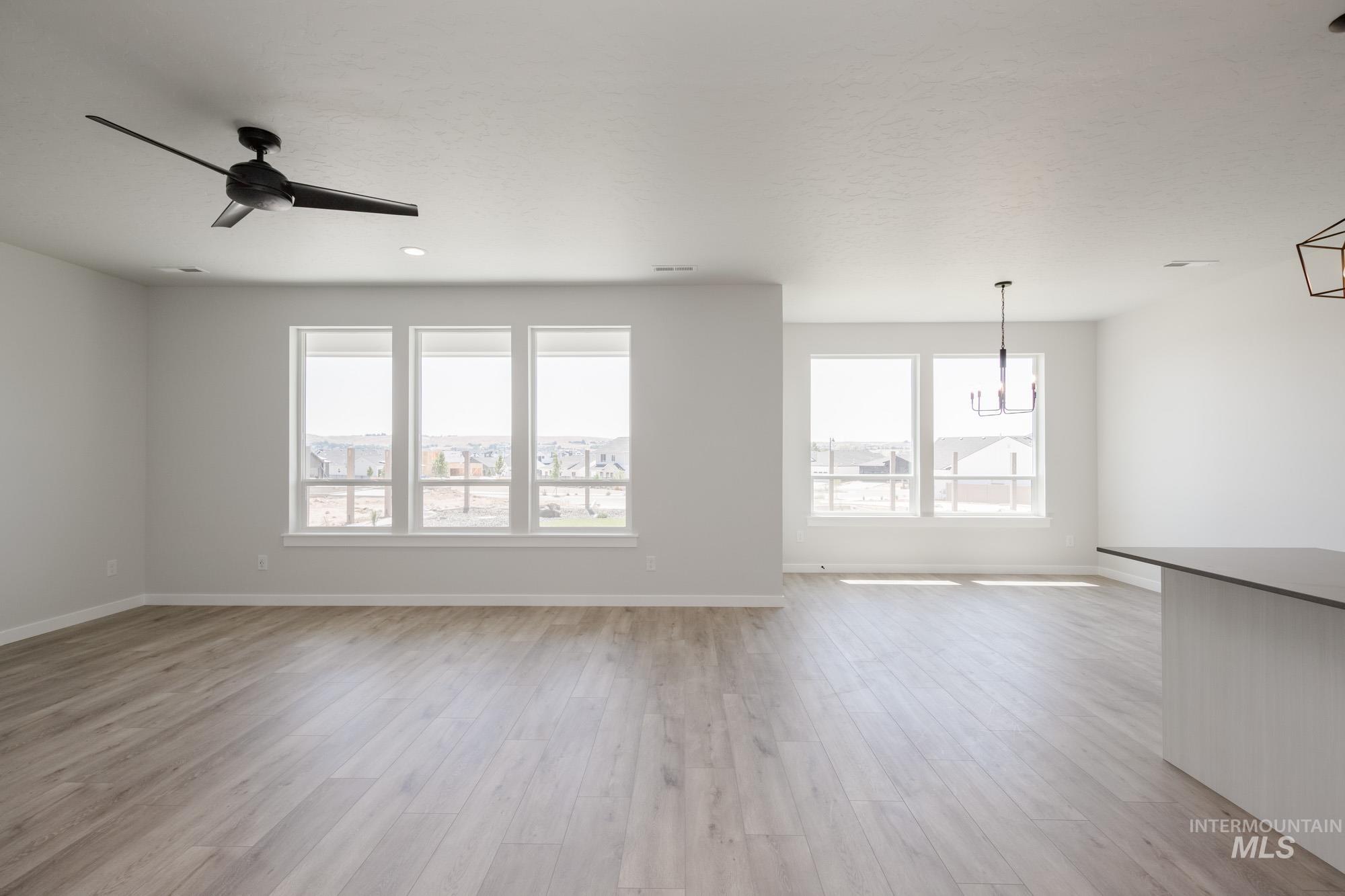 Unfurnished living room with light wood-type flooring and ceiling fan