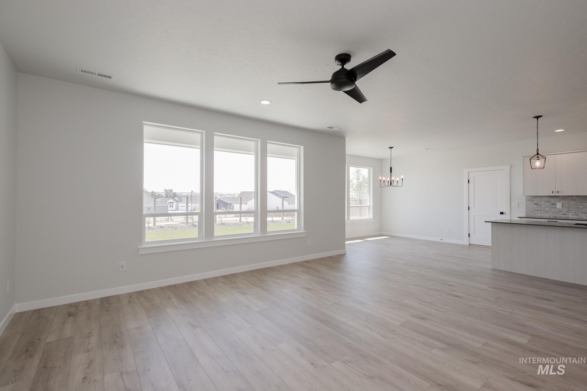 Unfurnished living room with light wood-style floors, a chandelier, ceiling fan, and recessed lighting