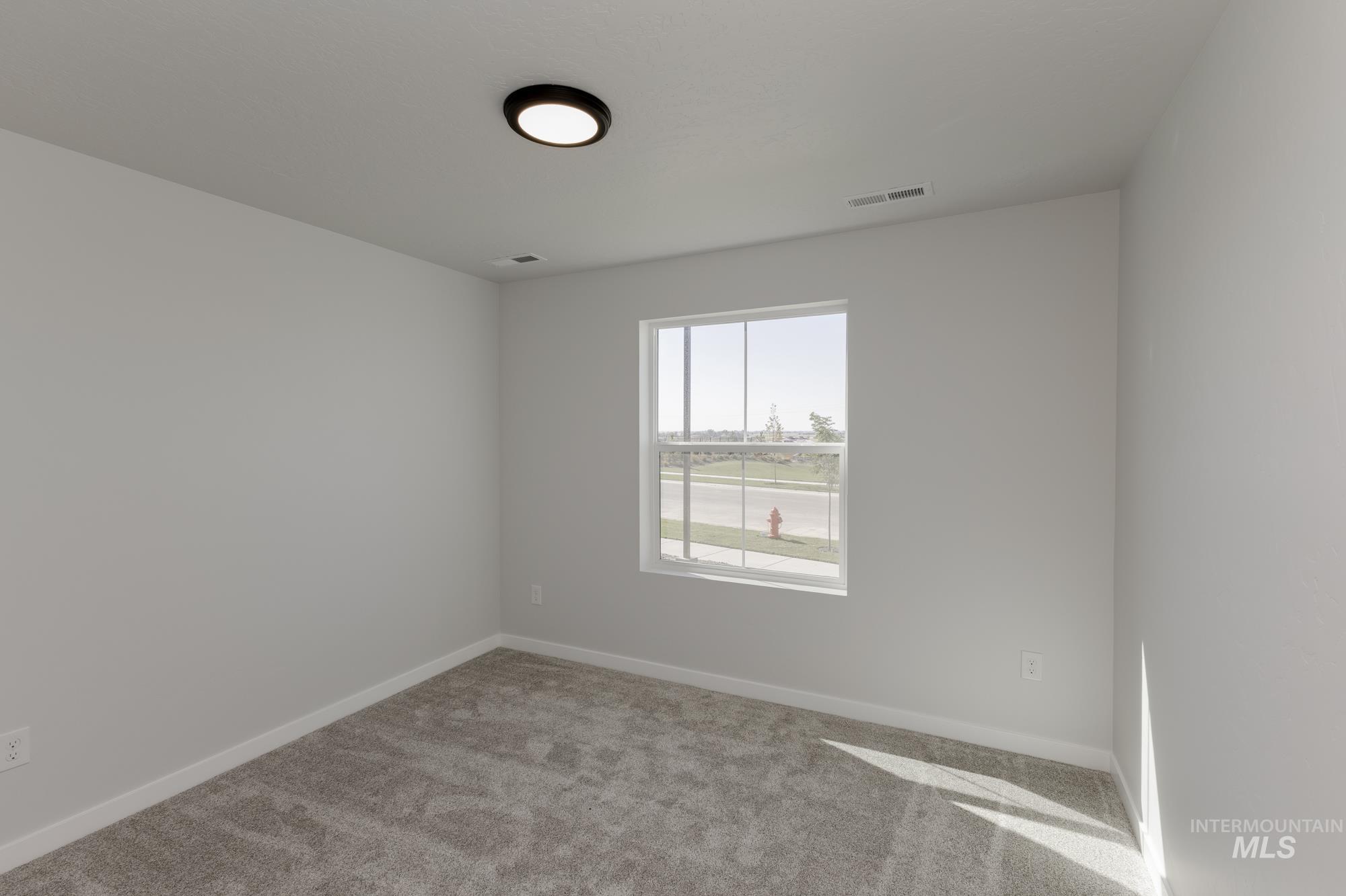 Unfurnished room featuring light carpet and baseboards