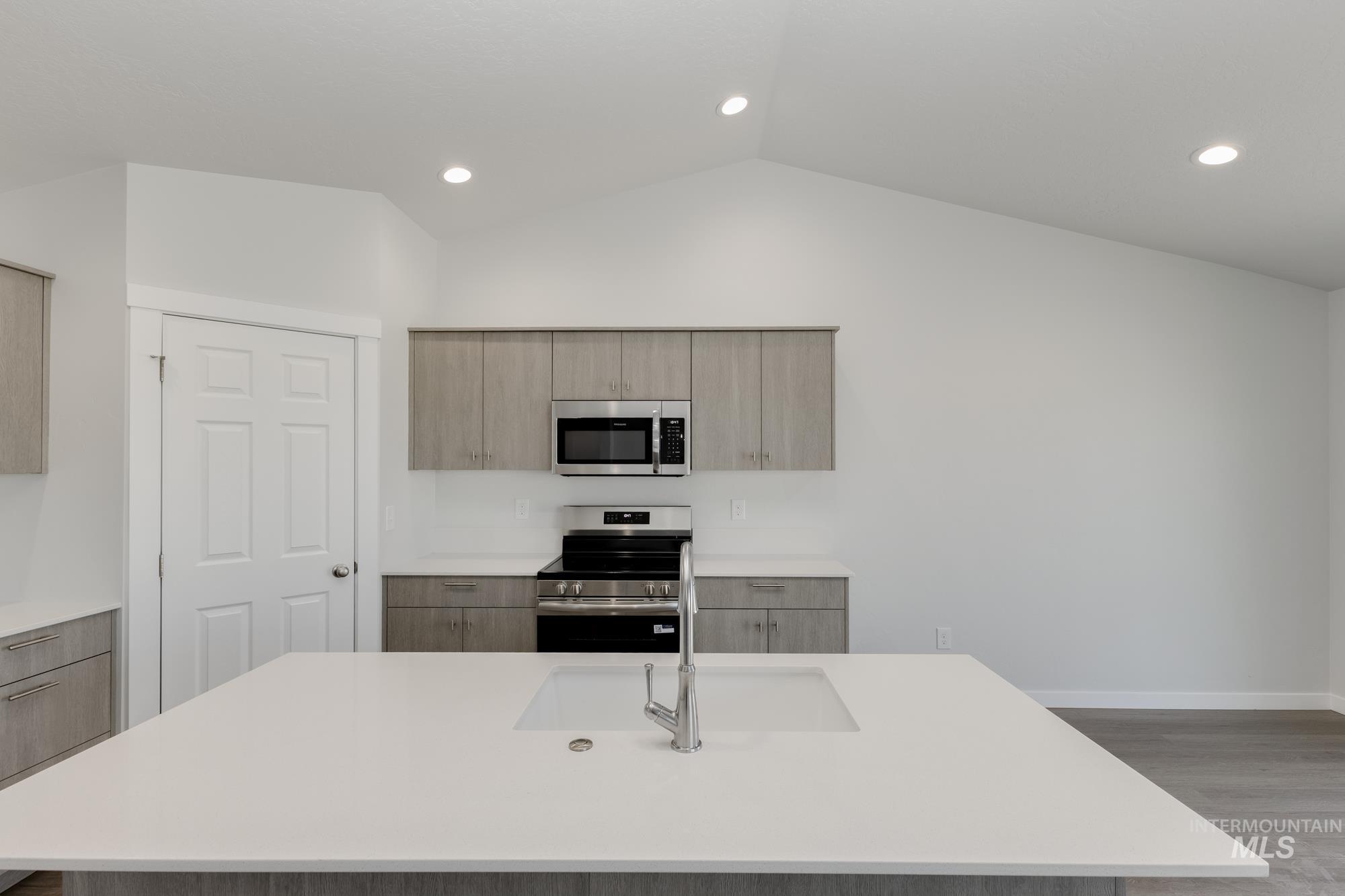 Kitchen with modern cabinets, appliances with stainless steel finishes, light wood-type flooring, recessed lighting, and light stone countertops