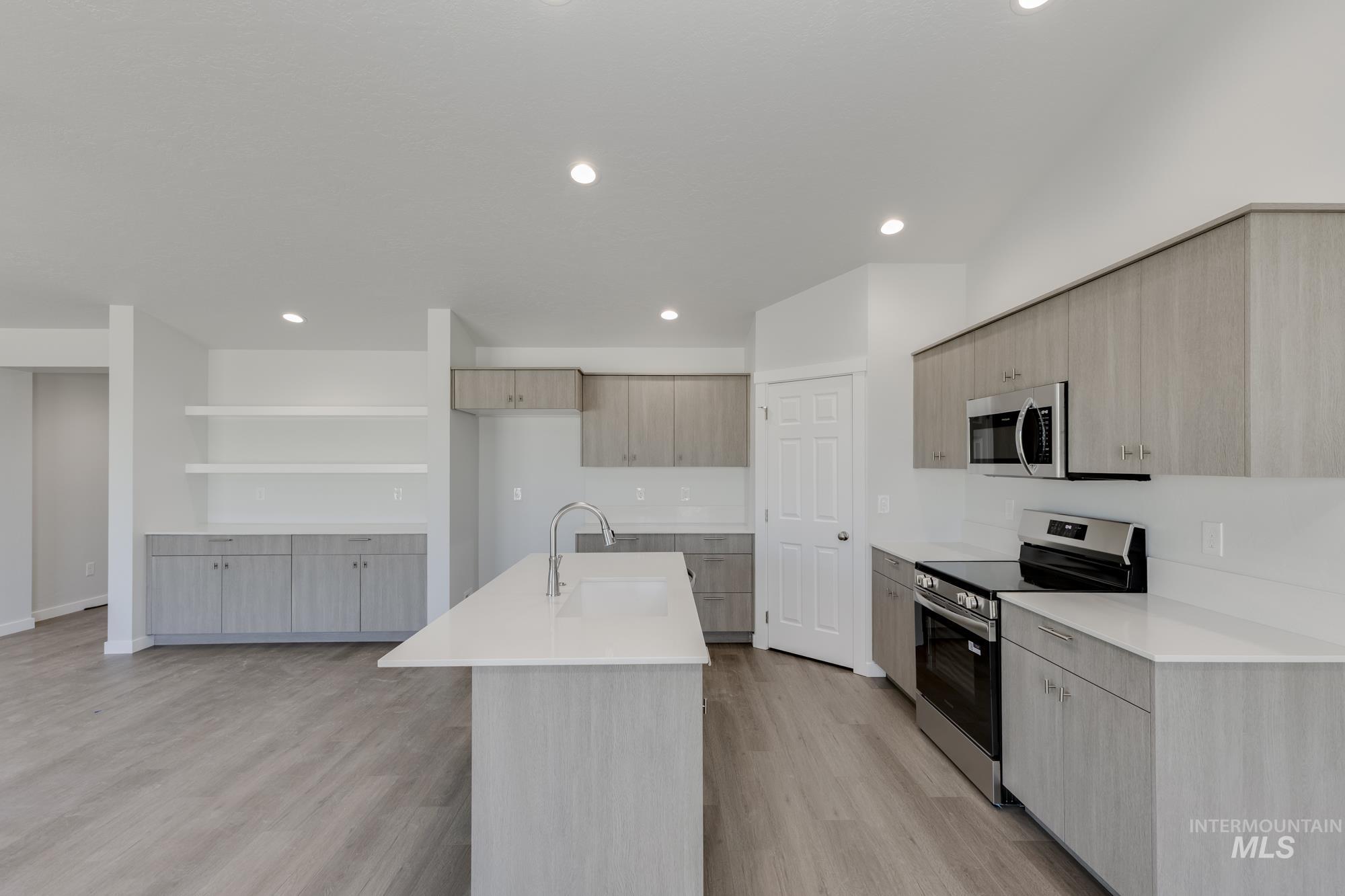 Kitchen with appliances with stainless steel finishes, modern cabinets, light wood-style floors, recessed lighting, and a center island with sink