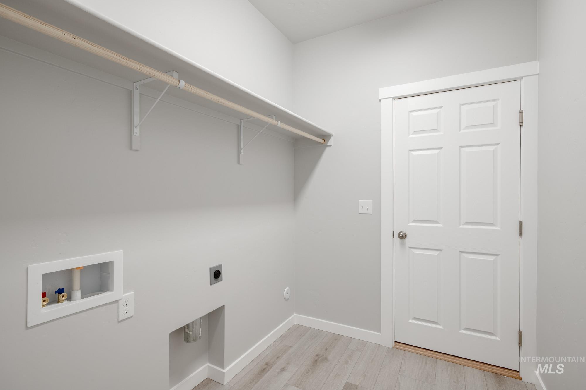 Laundry area with light wood-style floors, washer hookup, and electric dryer hookup
