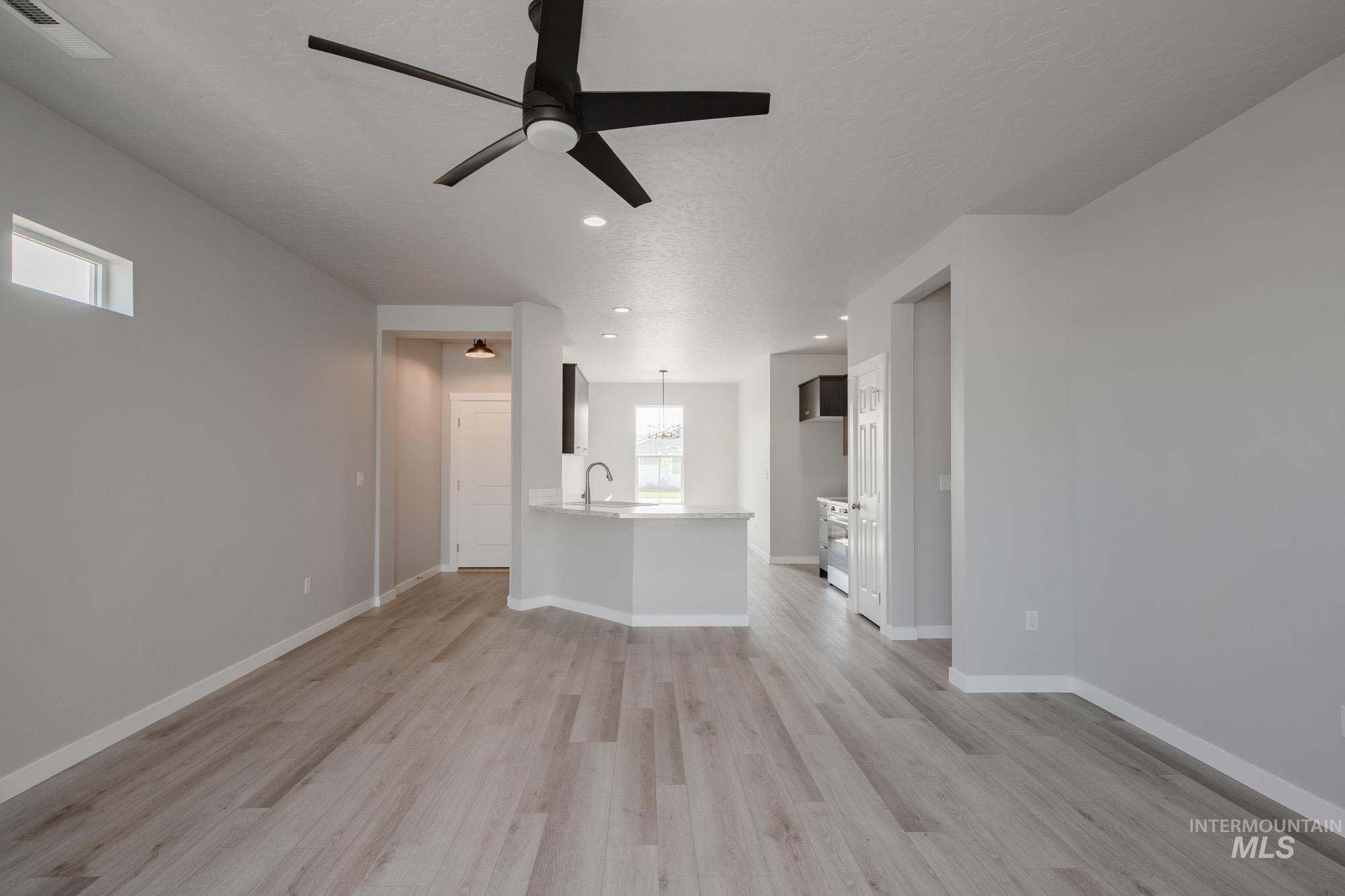 Unfurnished living room with light wood finished floors, ceiling fan, and recessed lighting