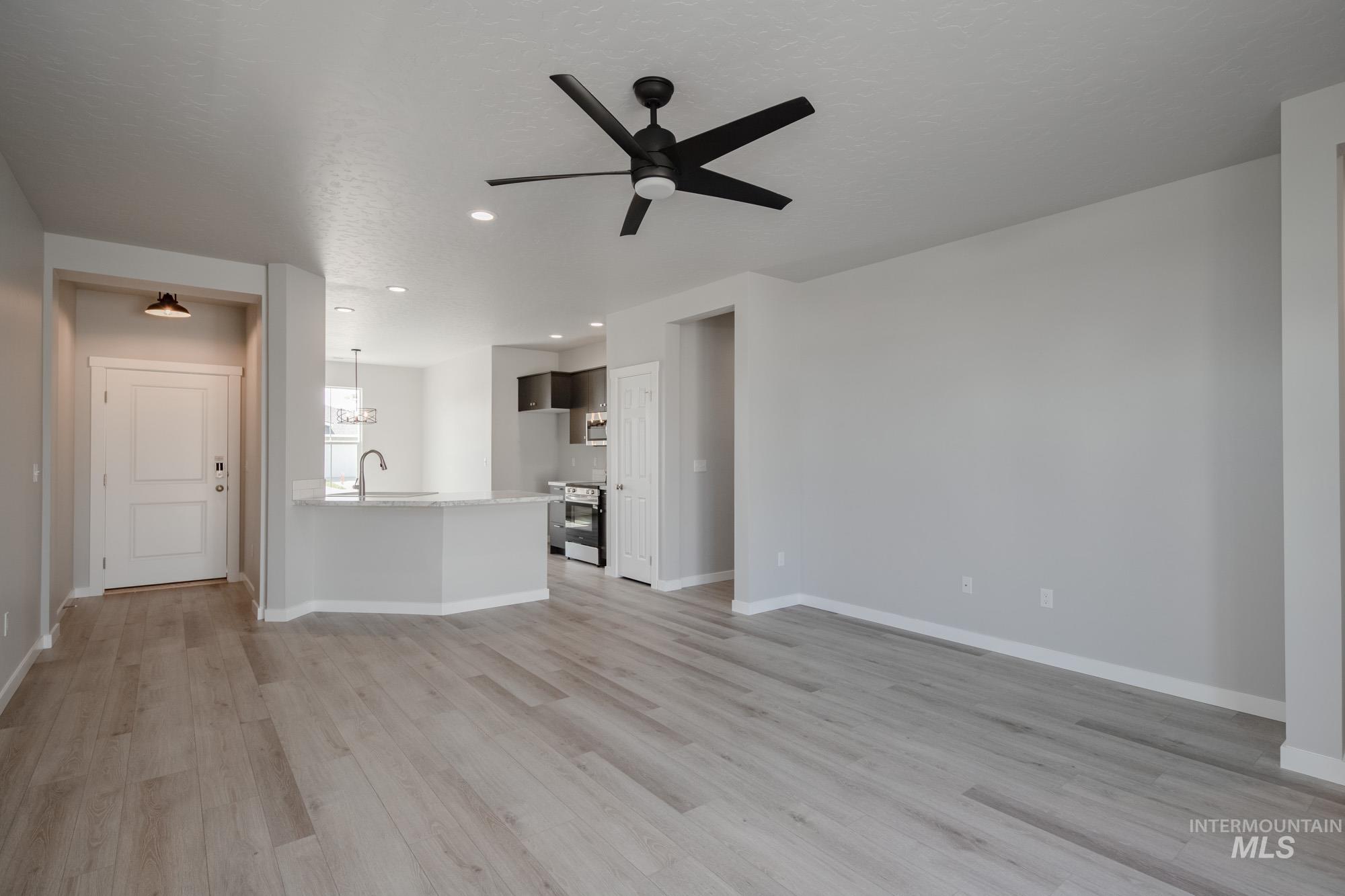Unfurnished living room featuring ceiling fan, light wood-style floors, recessed lighting, and a textured ceiling