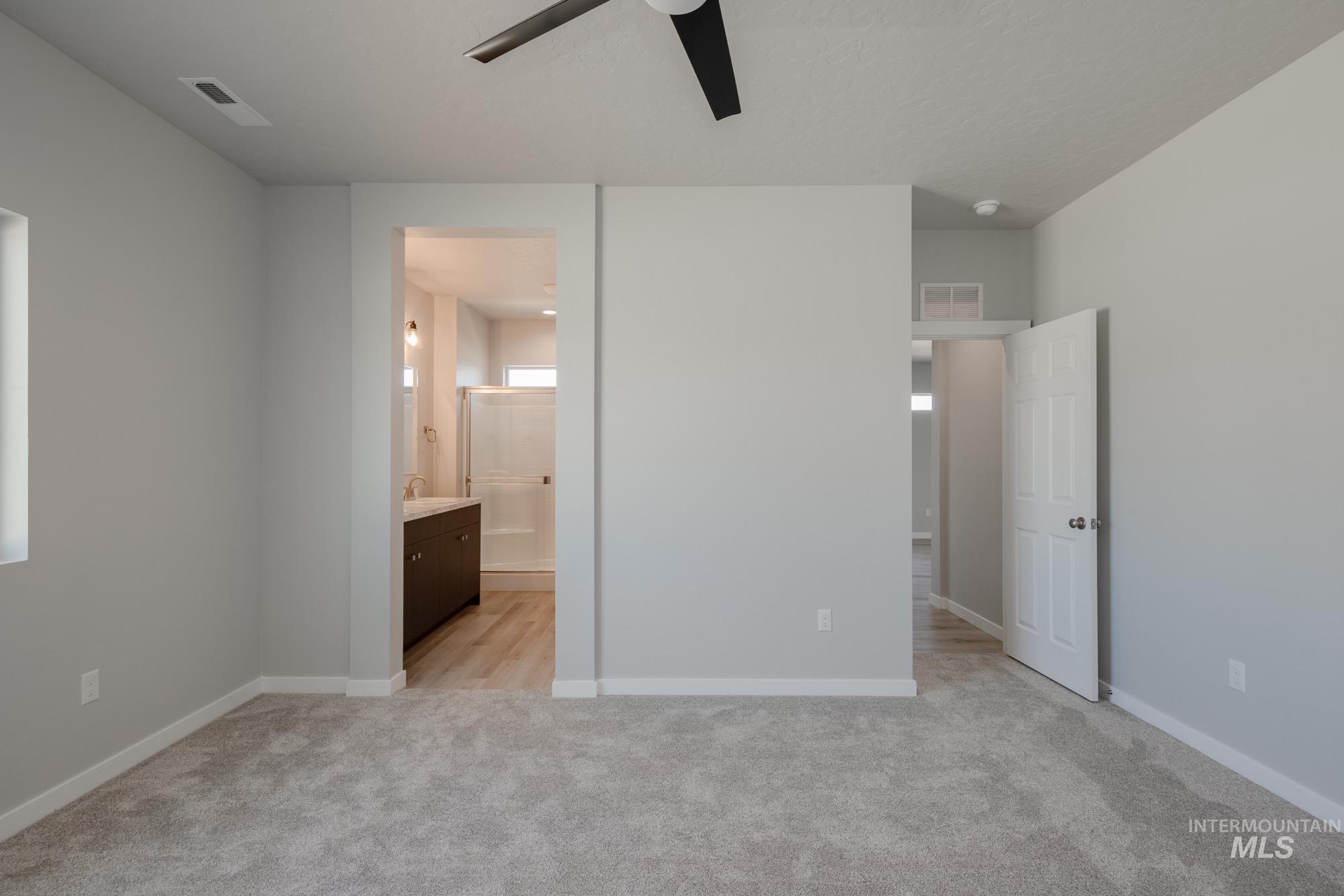 Unfurnished bedroom with light colored carpet, a ceiling fan, and ensuite bathroom