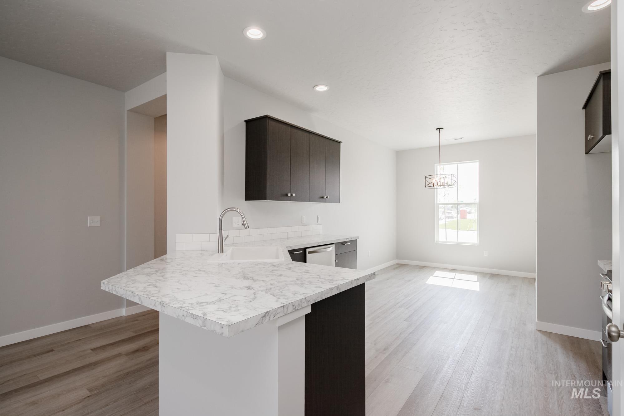 Kitchen featuring light countertops, a peninsula, light wood finished floors, hanging light fixtures, and recessed lighting
