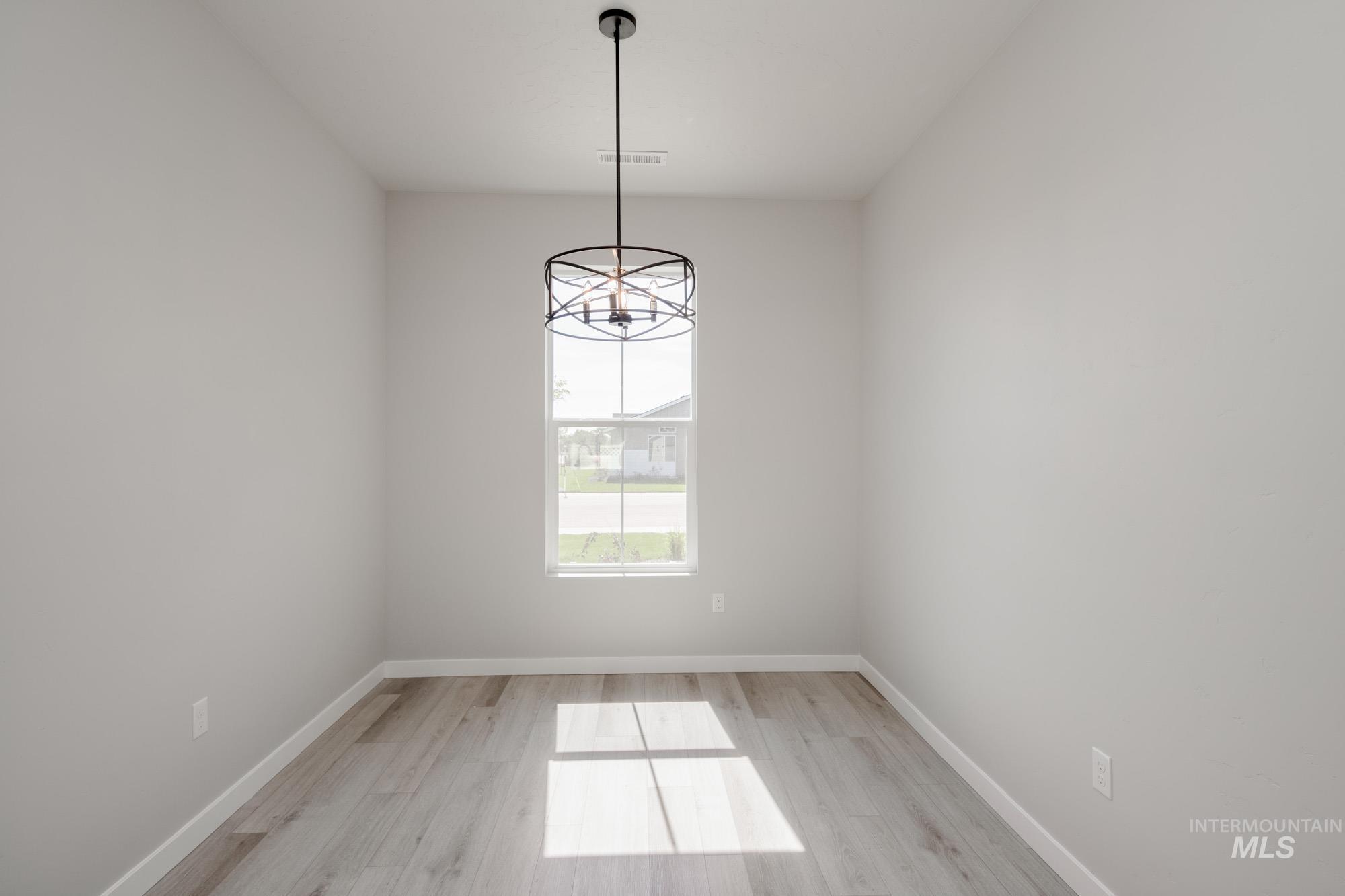 Spare room with a chandelier and light wood-style floors