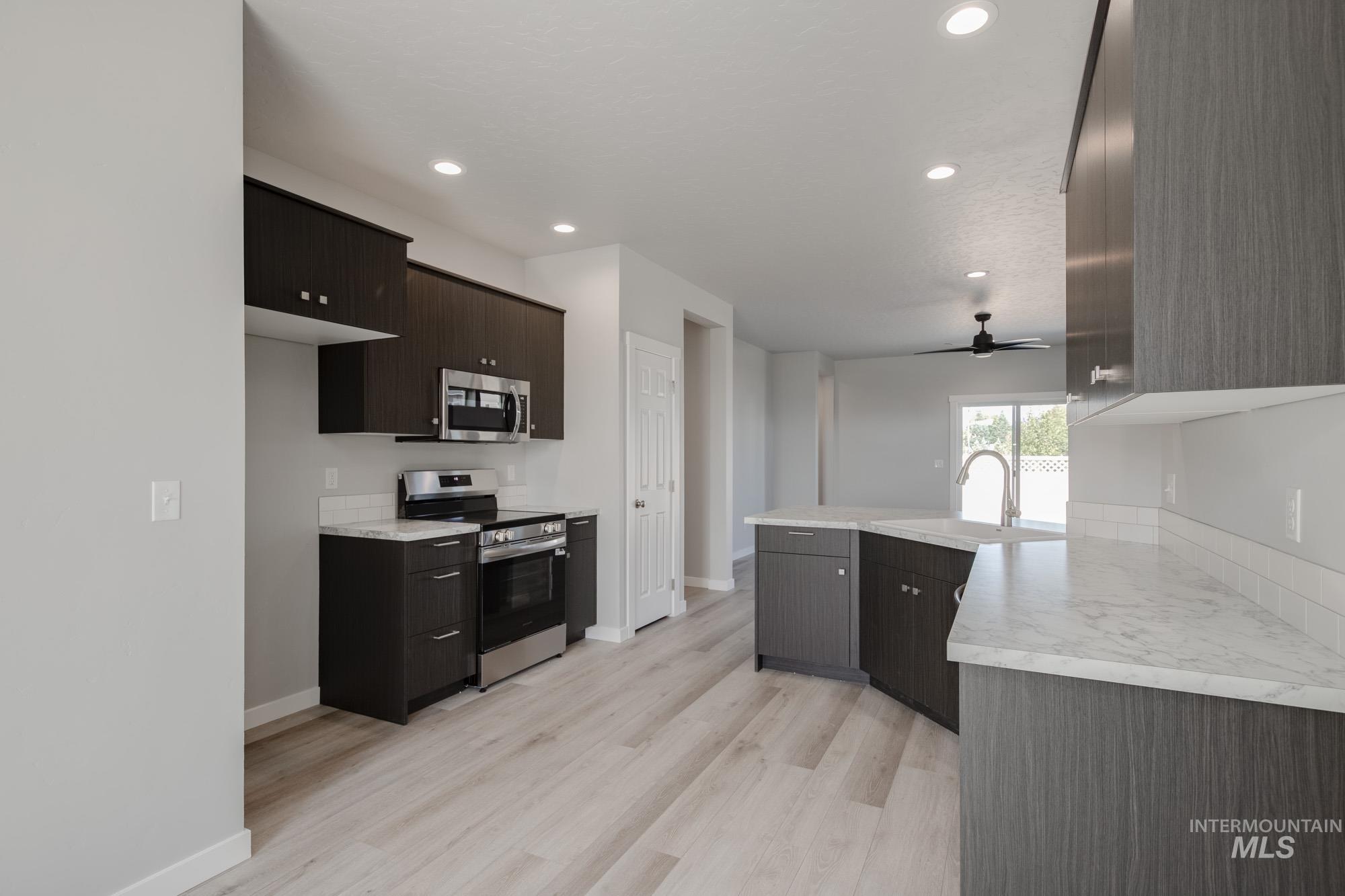 Kitchen featuring light countertops, stainless steel appliances, light wood-style floors, a ceiling fan, and recessed lighting