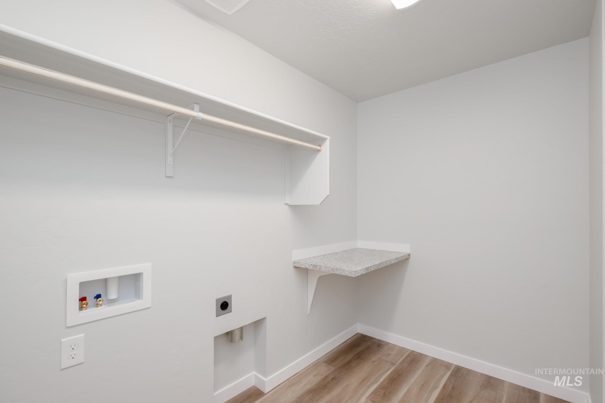 Laundry area with light wood-style floors, hookup for a washing machine, and electric dryer hookup