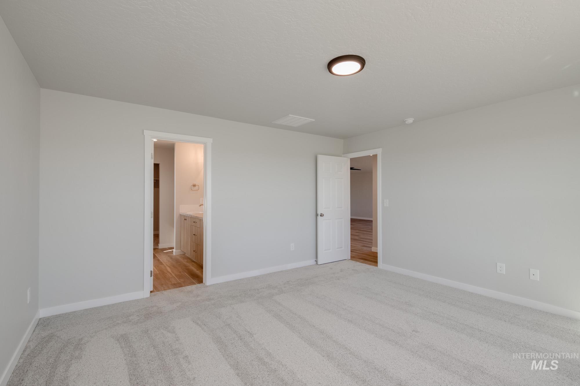 Unfurnished bedroom featuring light colored carpet and ensuite bath