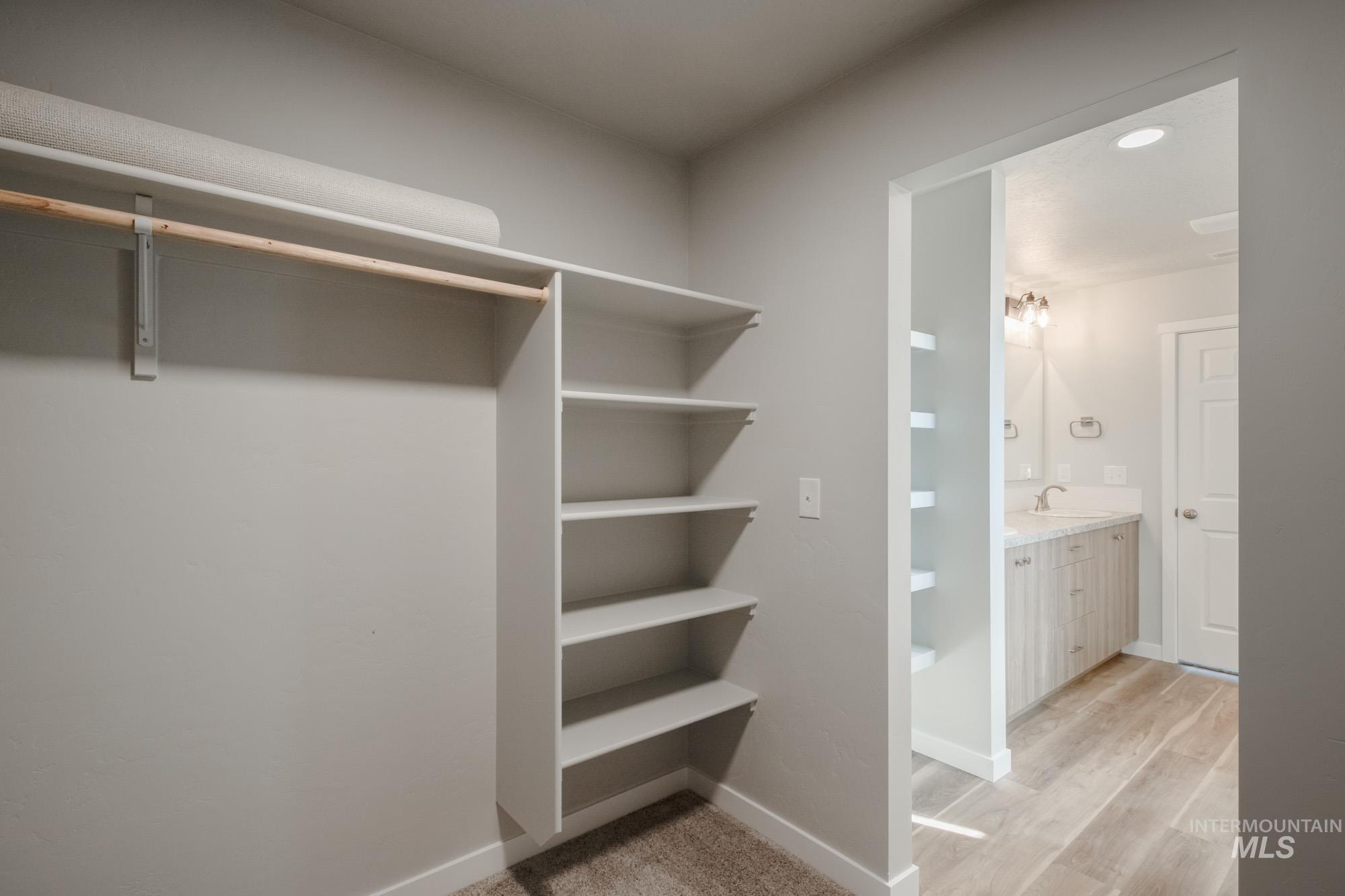 Walk in closet with light wood-style flooring