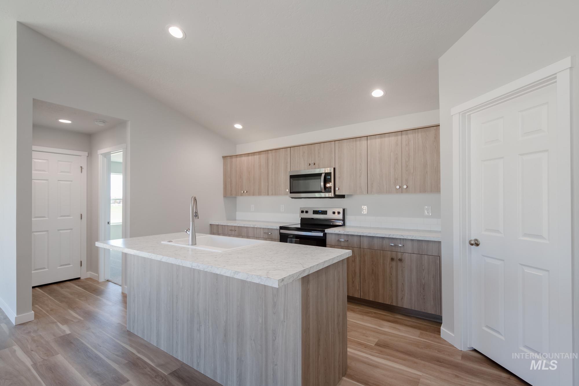 Kitchen featuring a kitchen island with sink, appliances with stainless steel finishes, light countertops, recessed lighting, and light wood-style floors