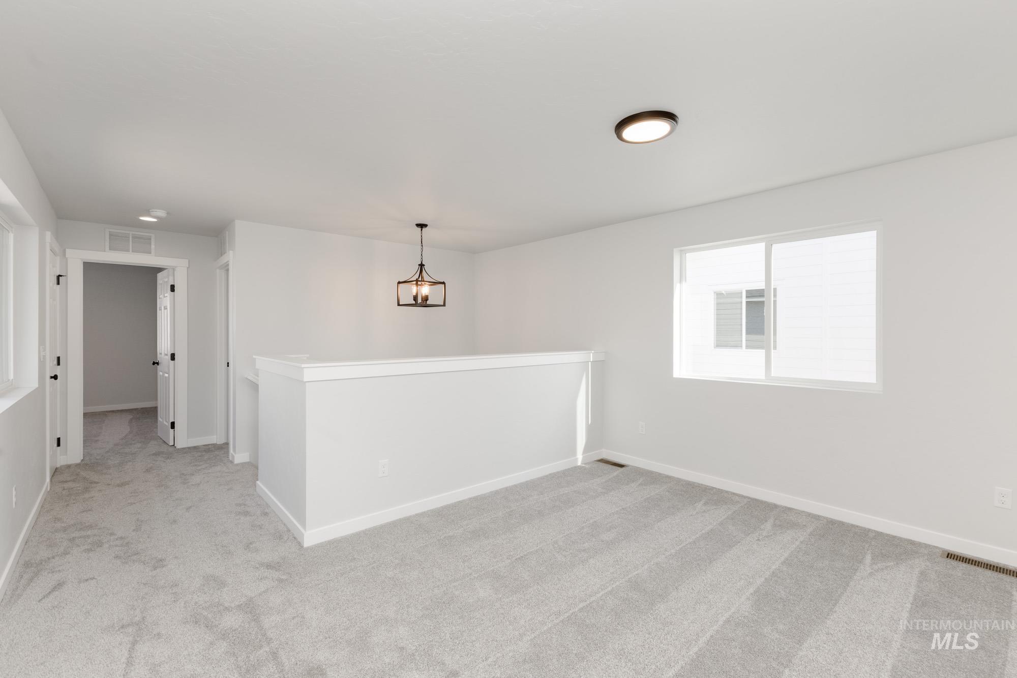 Spare room with light carpet and a chandelier