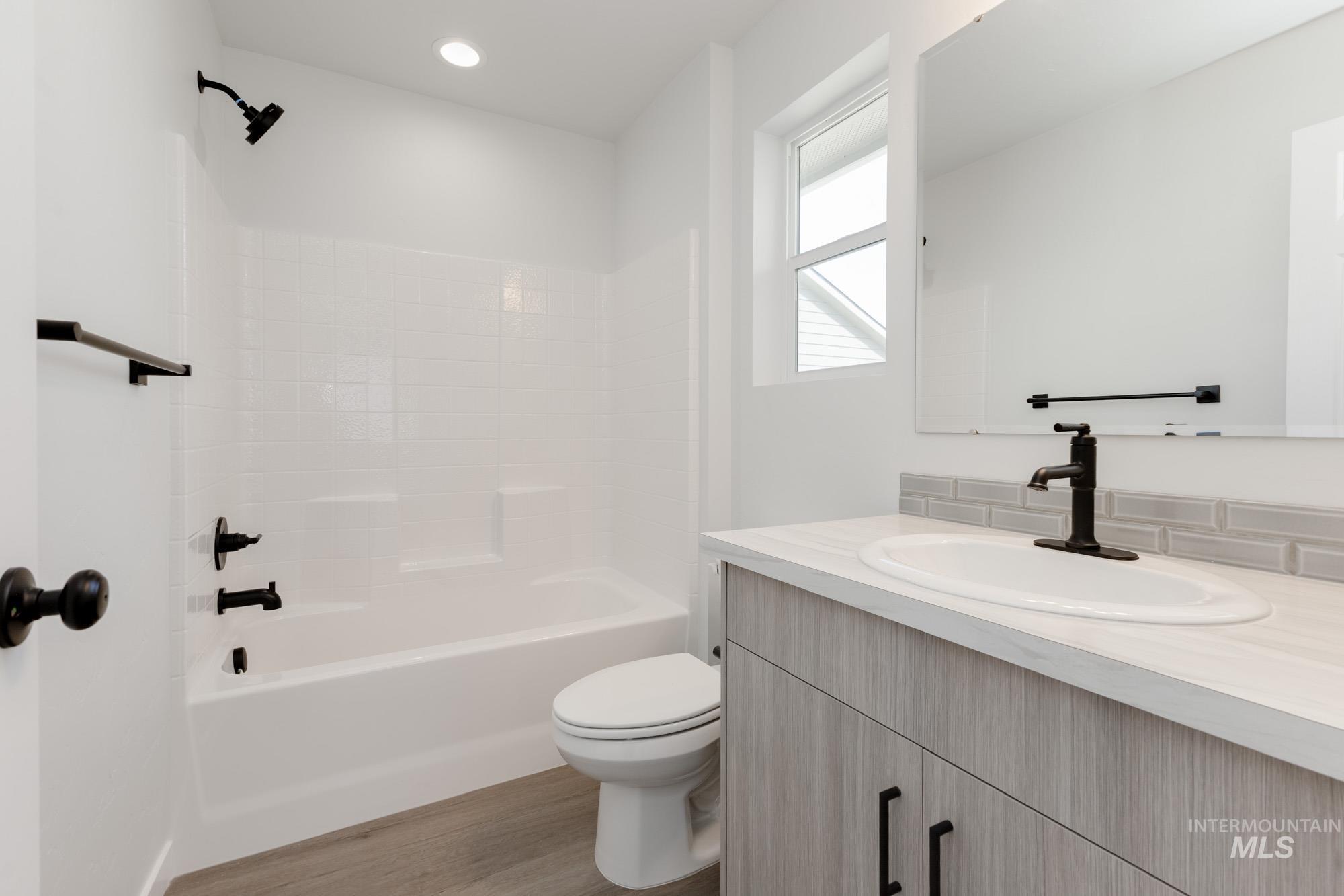Bathroom featuring vanity, washtub / shower combination, and light wood-type flooring