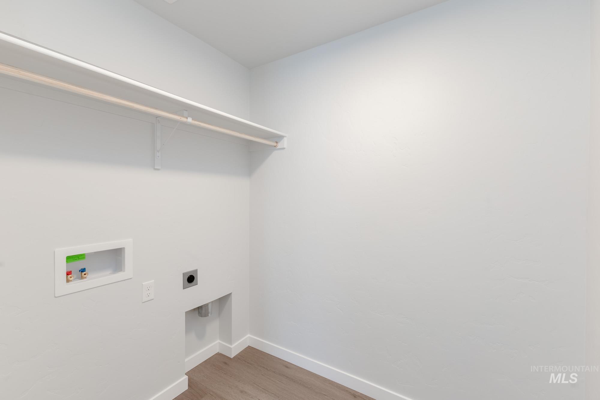 Laundry room with hookup for a washing machine, electric dryer hookup, and light wood-type flooring