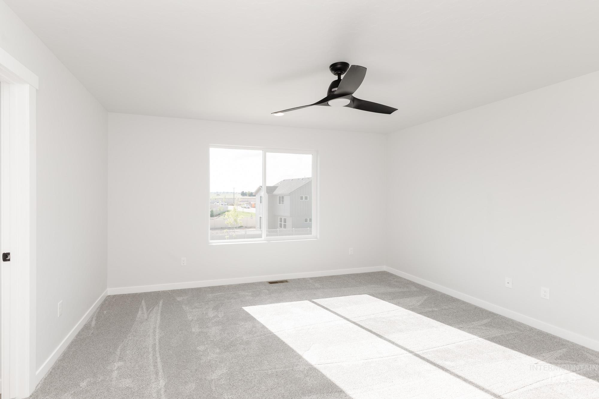Carpeted empty room with baseboards and a ceiling fan