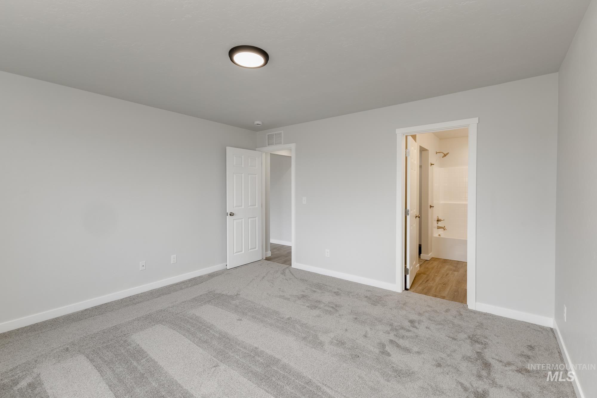 Unfurnished bedroom featuring carpet floors and ensuite bathroom