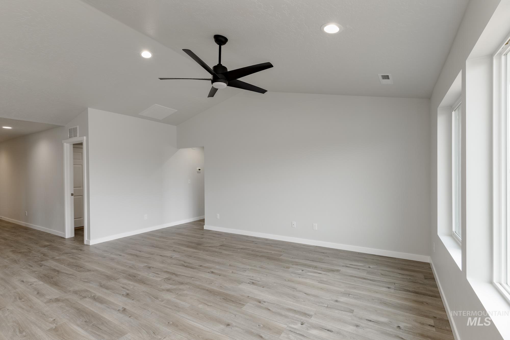 Empty room with recessed lighting, vaulted ceiling, light wood-type flooring, and ceiling fan
