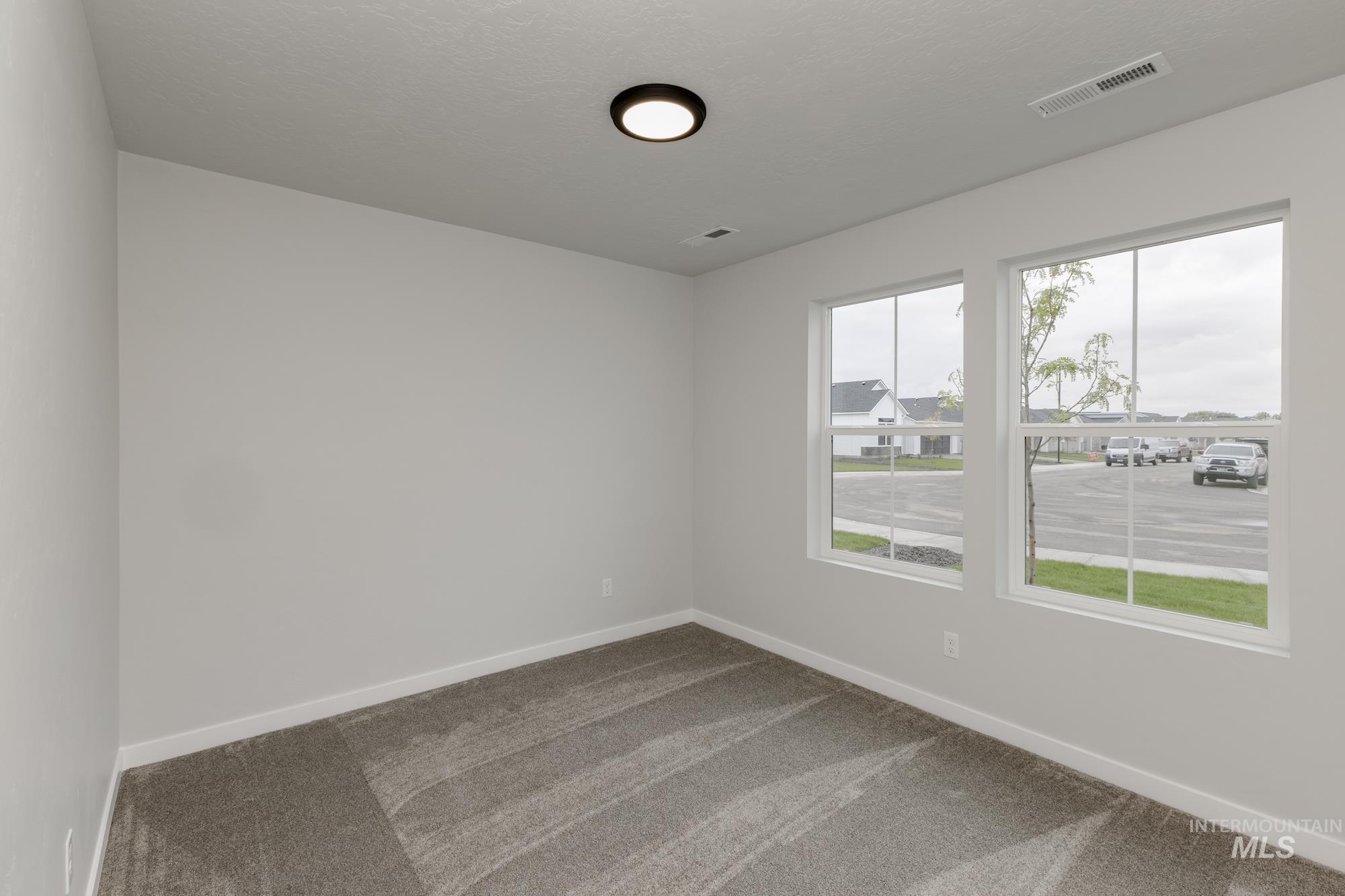 Carpeted spare room featuring baseboards