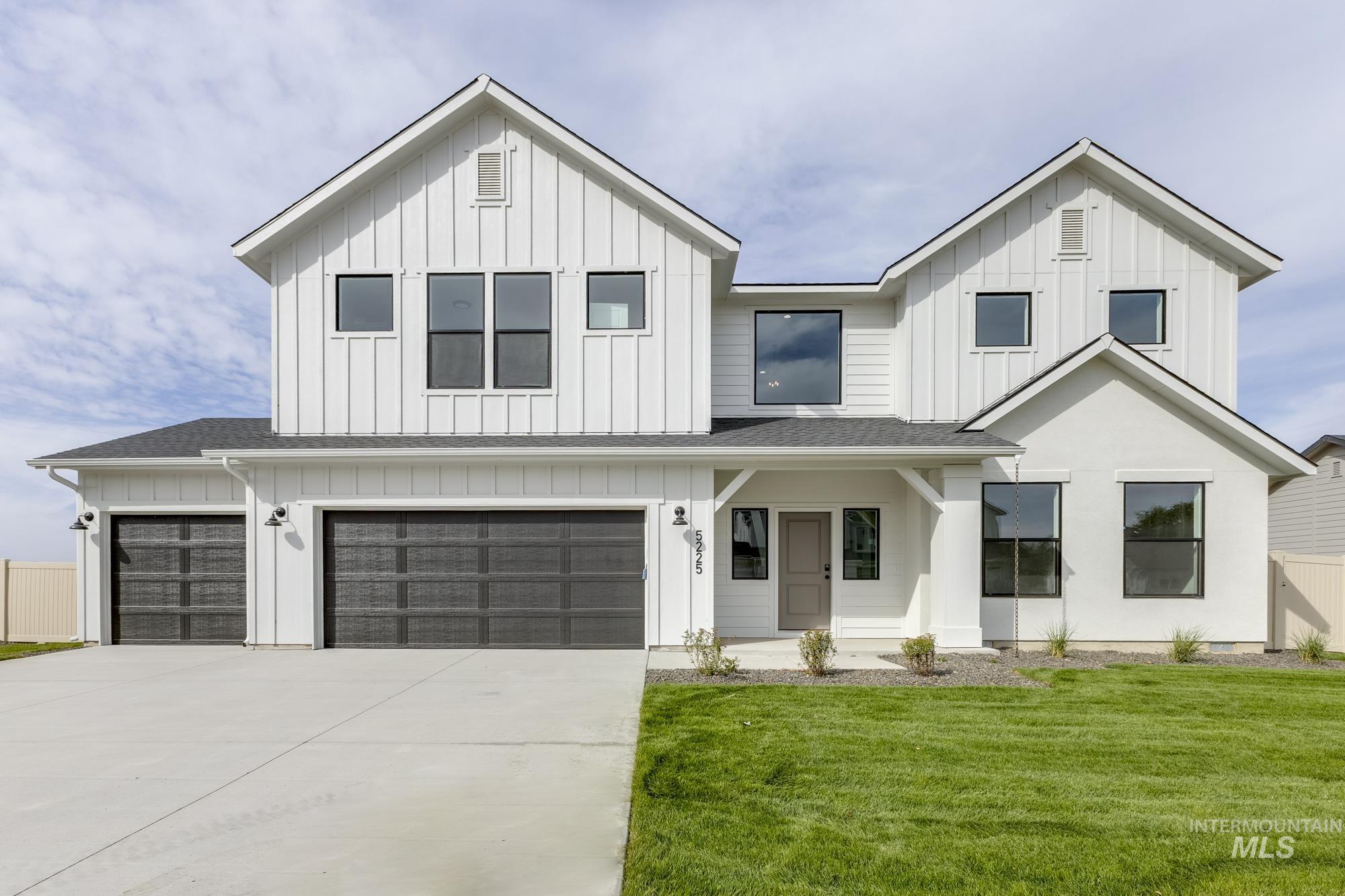 Modern farmhouse with board and batten siding, a garage, covered porch, and roof with shingles