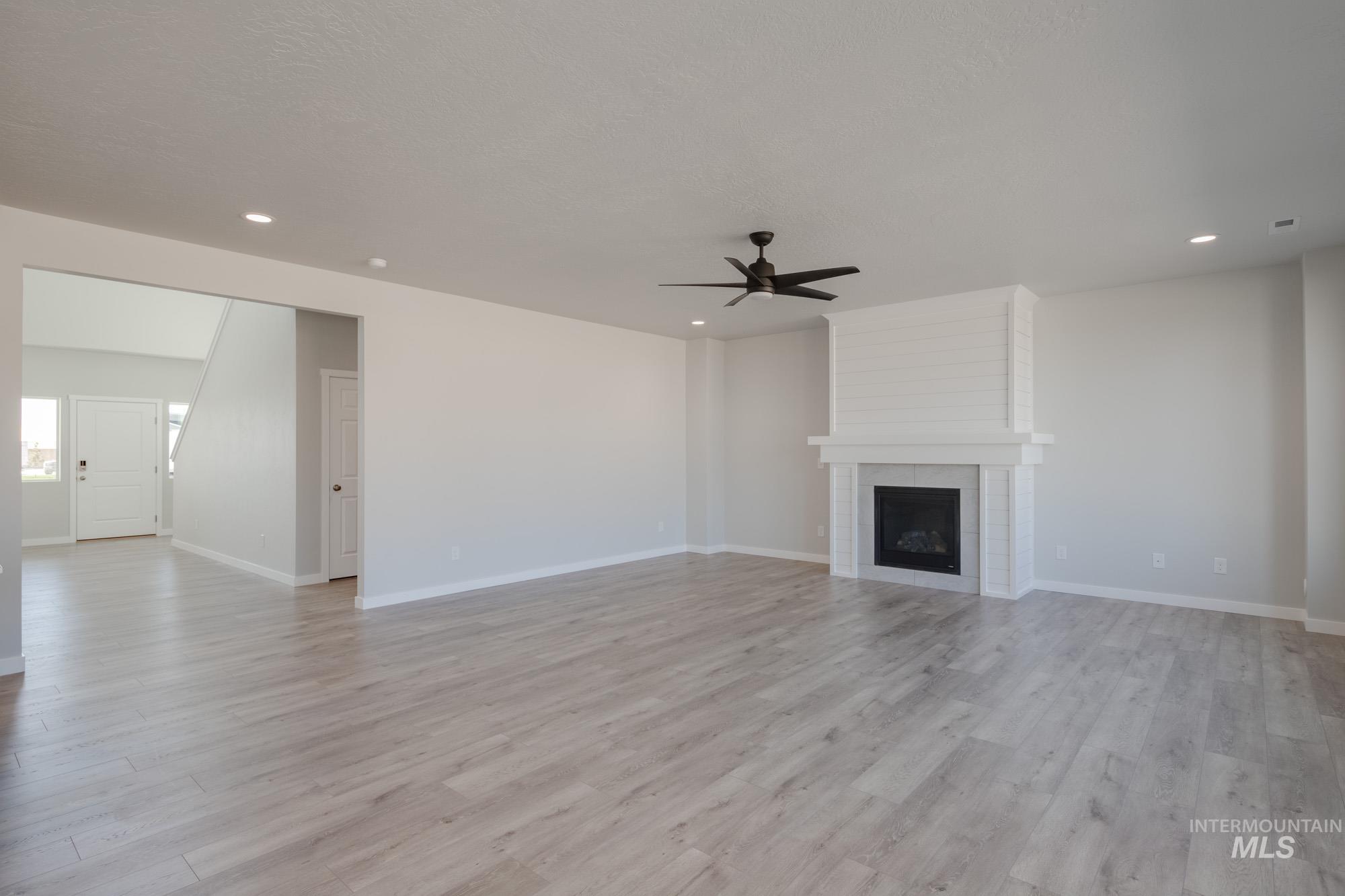 Unfurnished living room with light wood-style floors, a fireplace, recessed lighting, and a ceiling fan