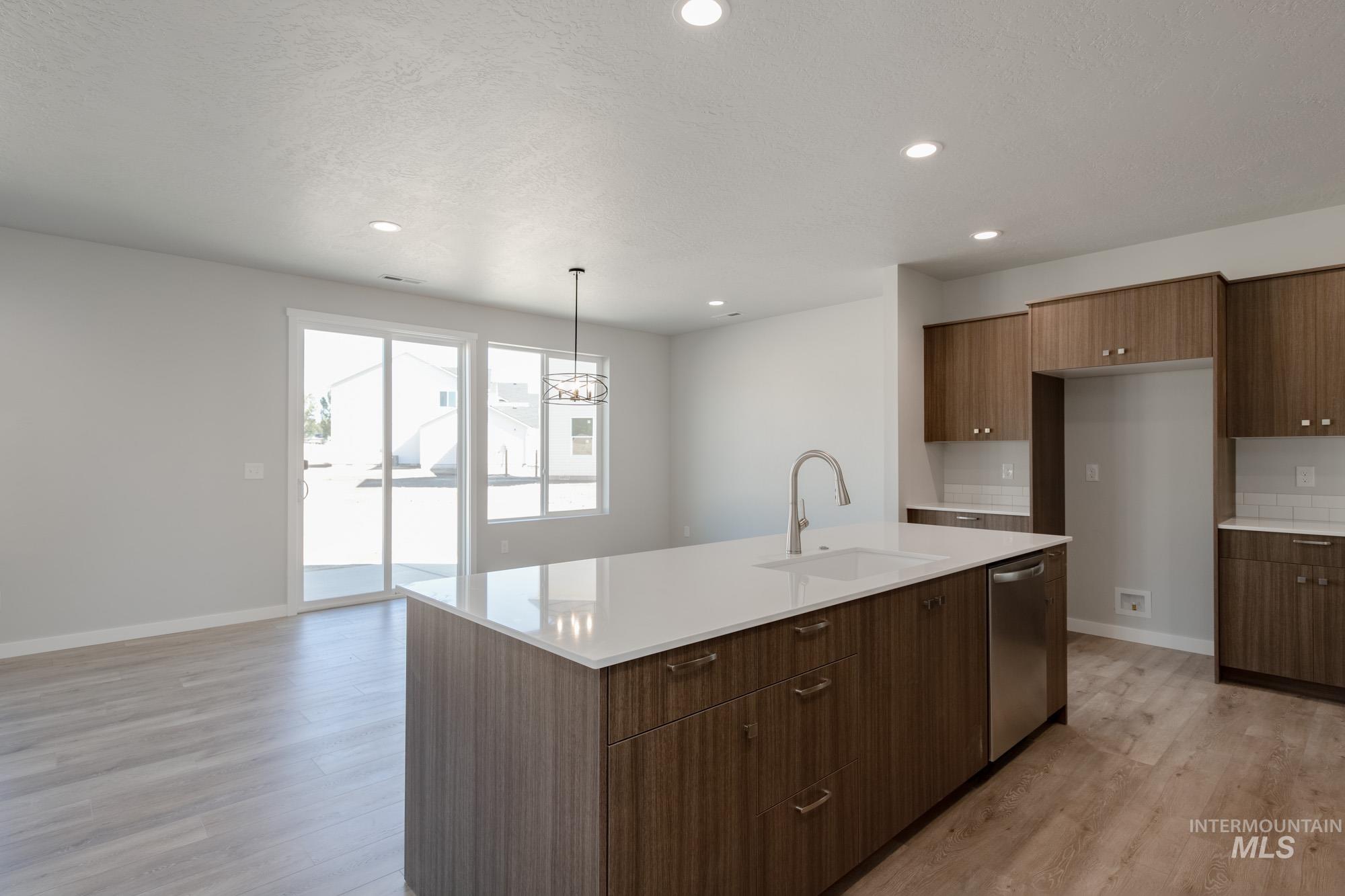 Kitchen with recessed lighting, a chandelier, an island with sink, light wood finished floors, and modern cabinets