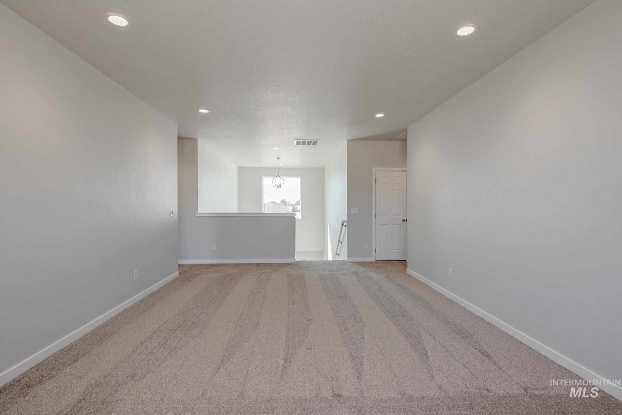 Spare room featuring carpet floors, recessed lighting, and a chandelier