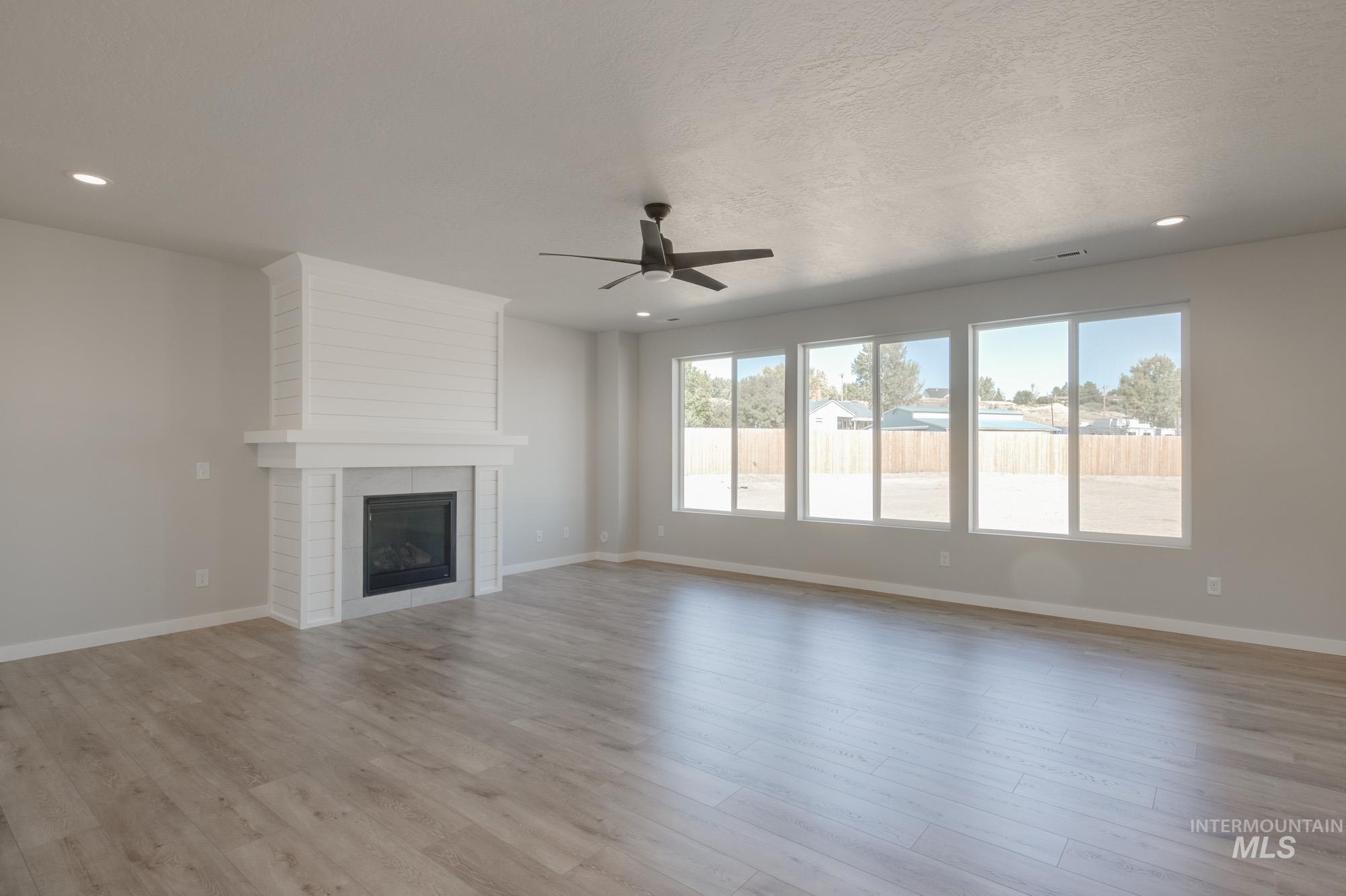 Unfurnished living room with a fireplace, a ceiling fan, light wood-type flooring, and recessed lighting