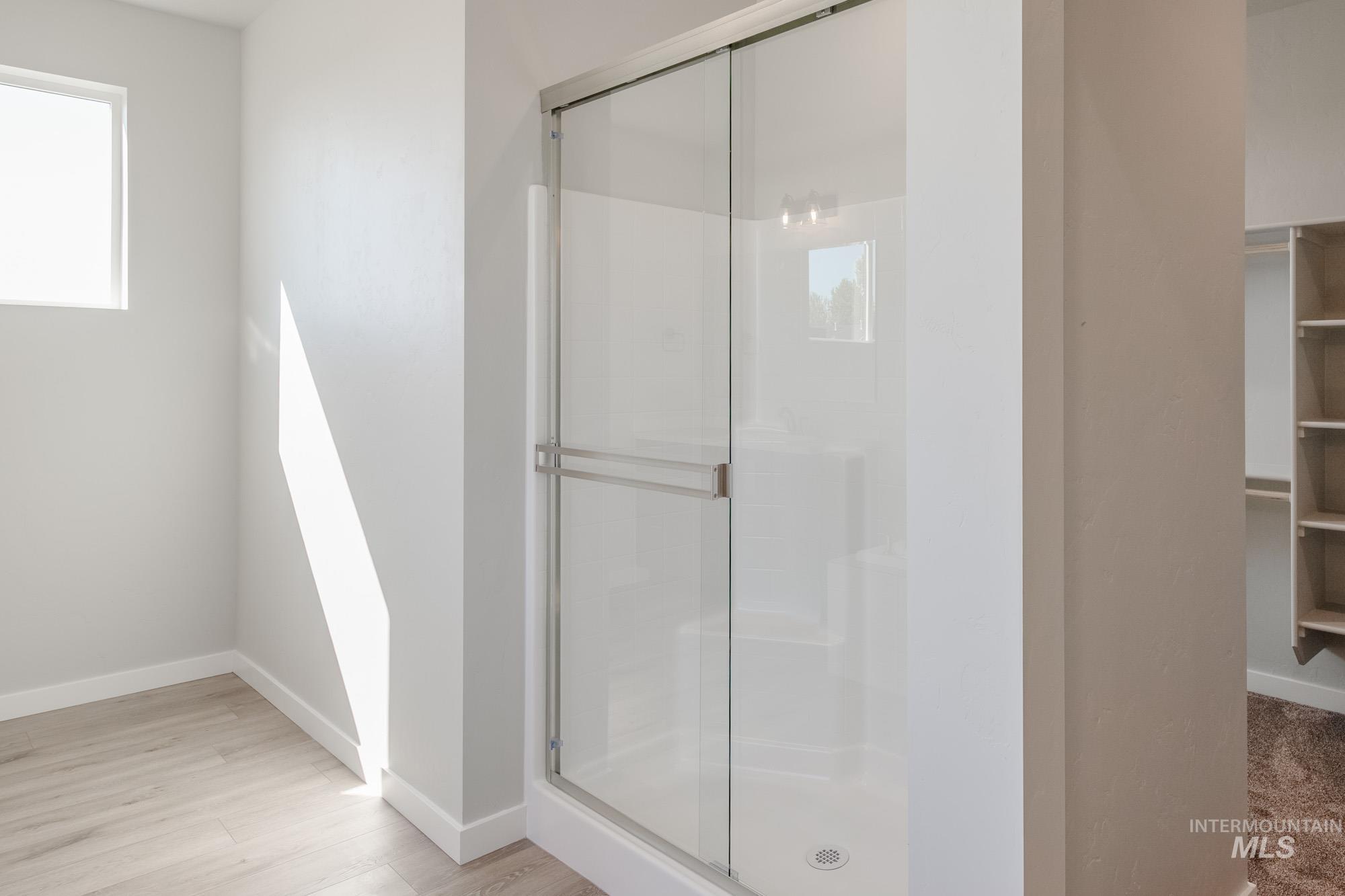 Full bath with a stall shower, light wood-type flooring, and a spacious closet