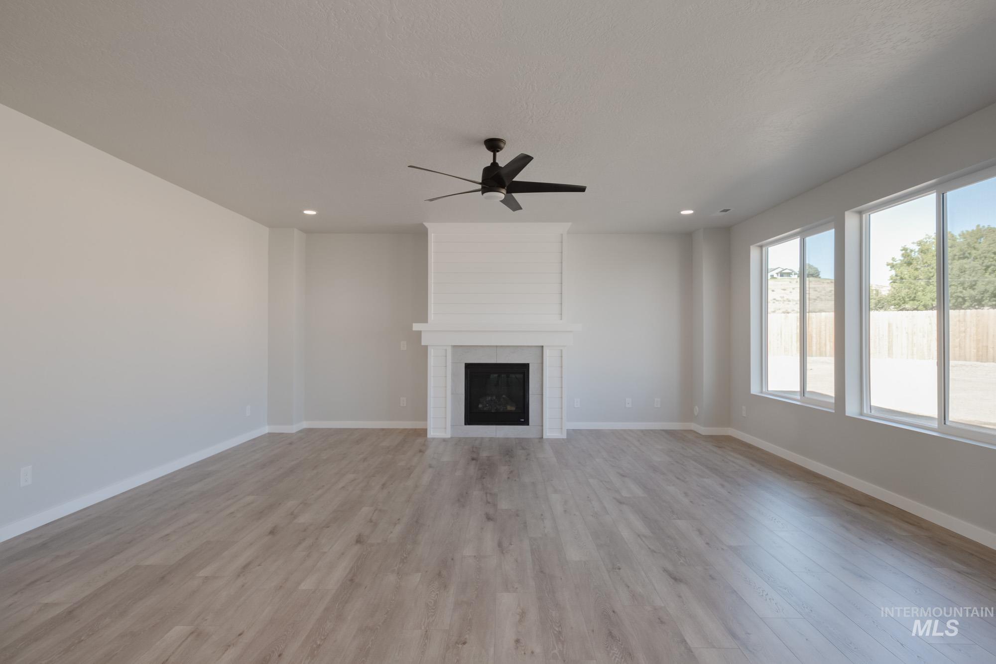 Unfurnished living room with a fireplace, light wood-style floors, a ceiling fan, and recessed lighting