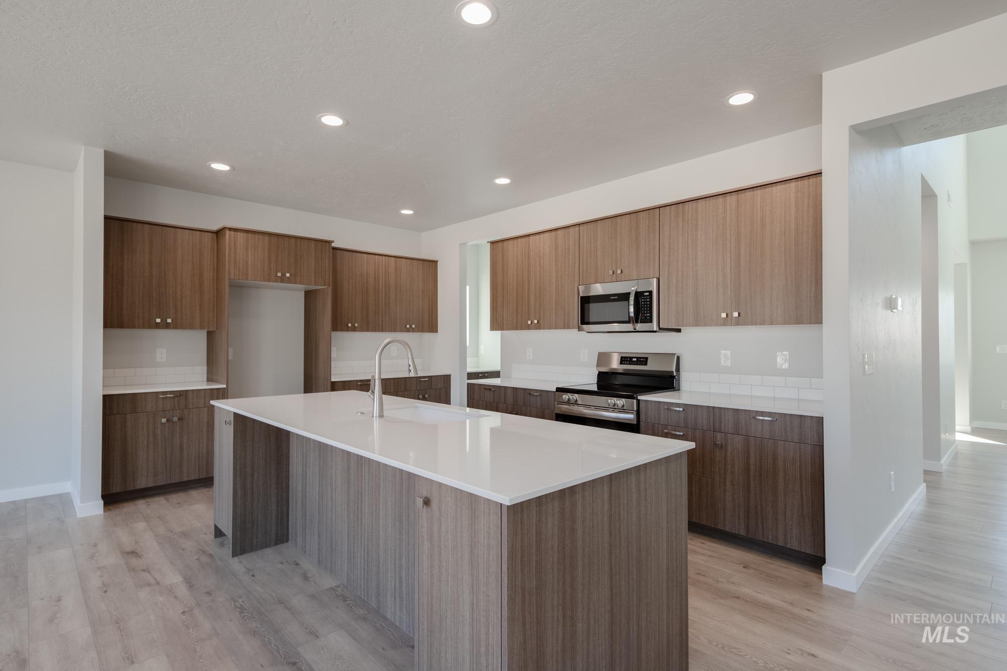 Kitchen featuring stainless steel appliances, modern cabinets, light wood-type flooring, a kitchen island with sink, and recessed lighting