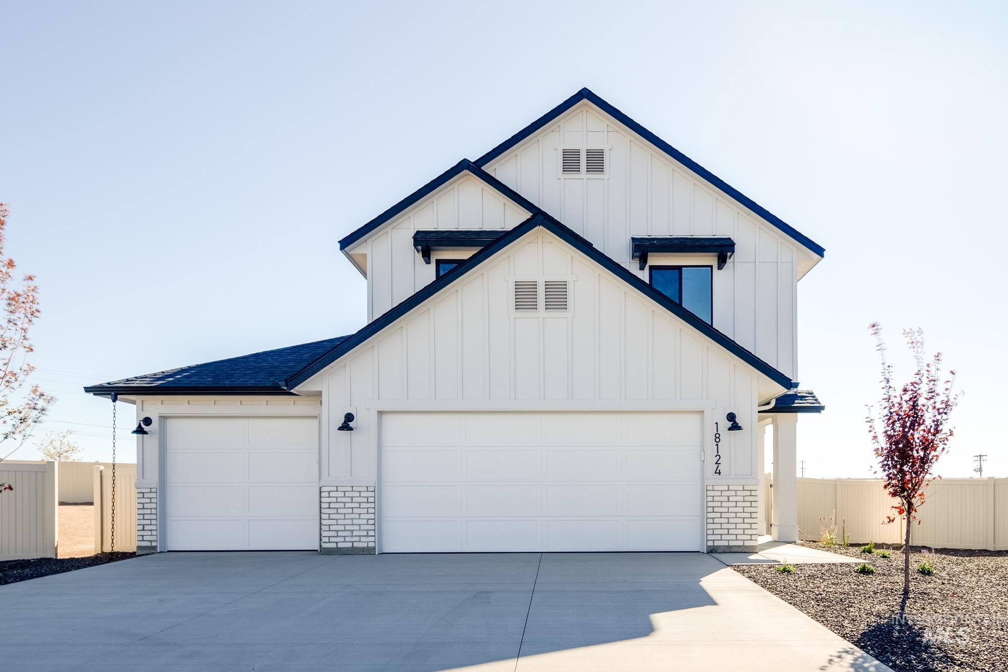Modern farmhouse style home featuring board and batten siding, driveway, brick siding, and a shingled roof