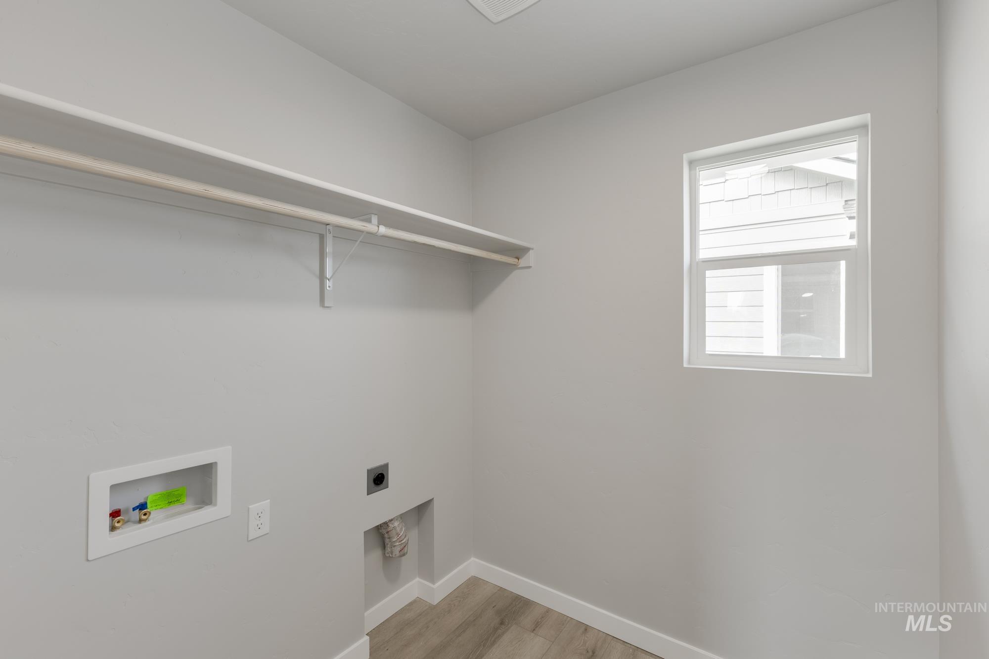 Laundry room with light wood-type flooring, hookup for an electric dryer, and washer hookup