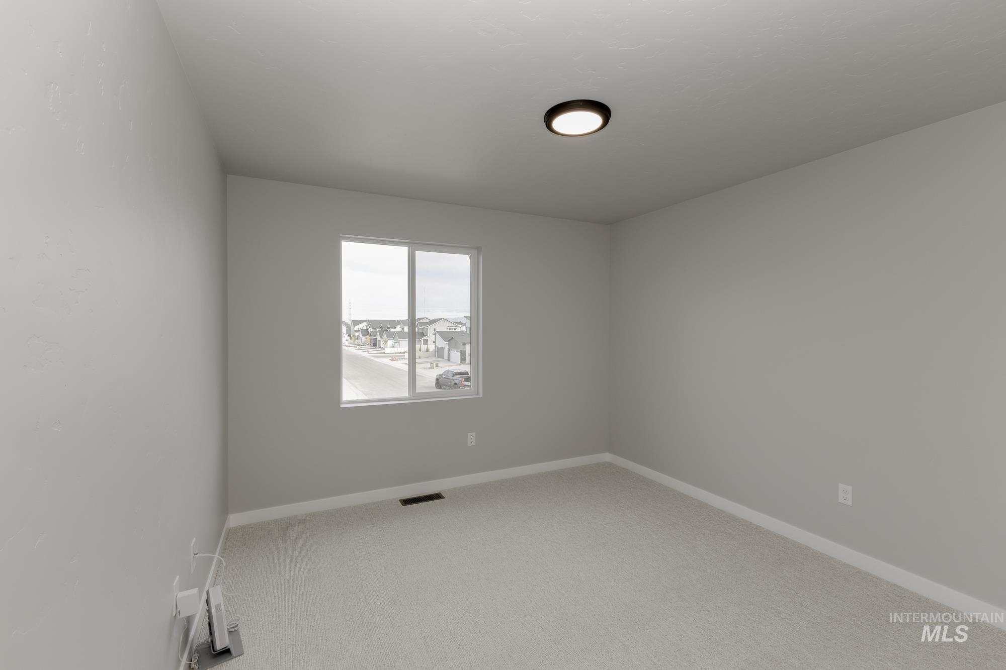 Empty room featuring light colored carpet and baseboards